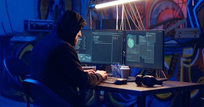 Hacker using computer to target vulnerable unpatched connections. How Can We Protect Ourselves from Cybercrime?