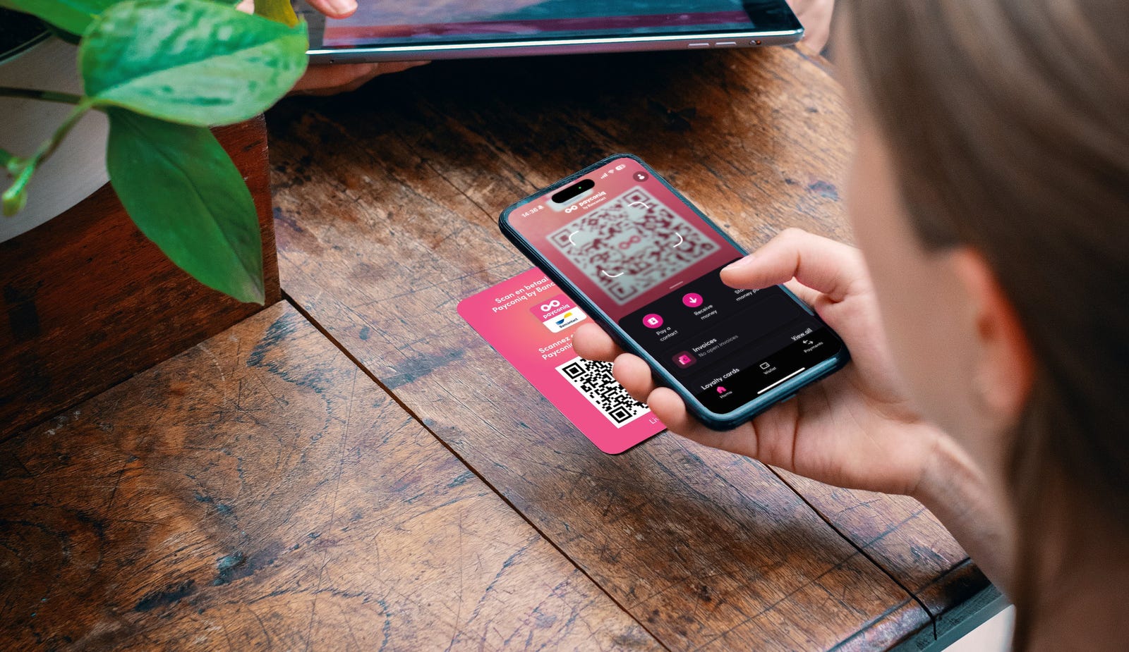 Een persoon met een telefoon en een qr-code op de Sticker oplossing van Payconiq by Bancontact