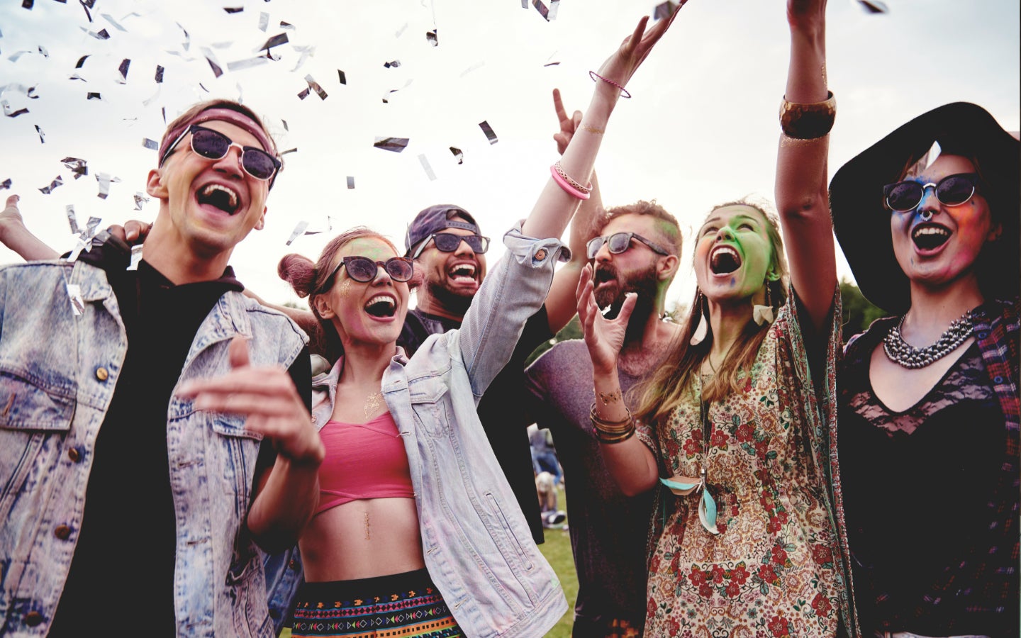 A group of festival-goers throw confetti in the air