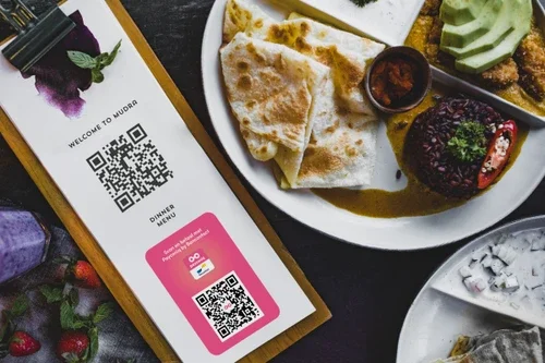 A plate of food next to a menu with a qr code