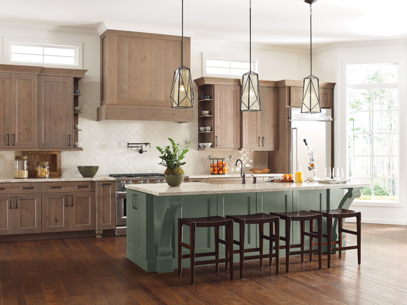 A sage green kitchen island with wood cabinets.