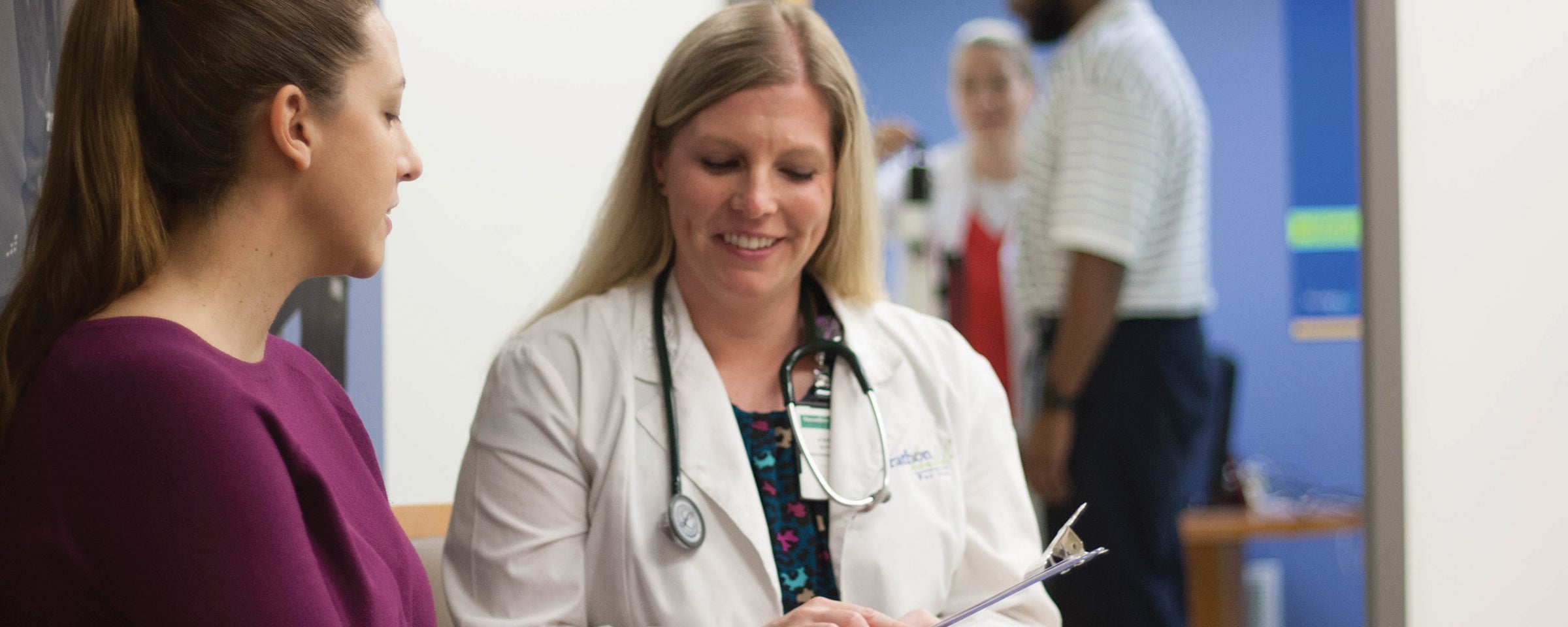 Doctor holding clipboard while sitting with patient