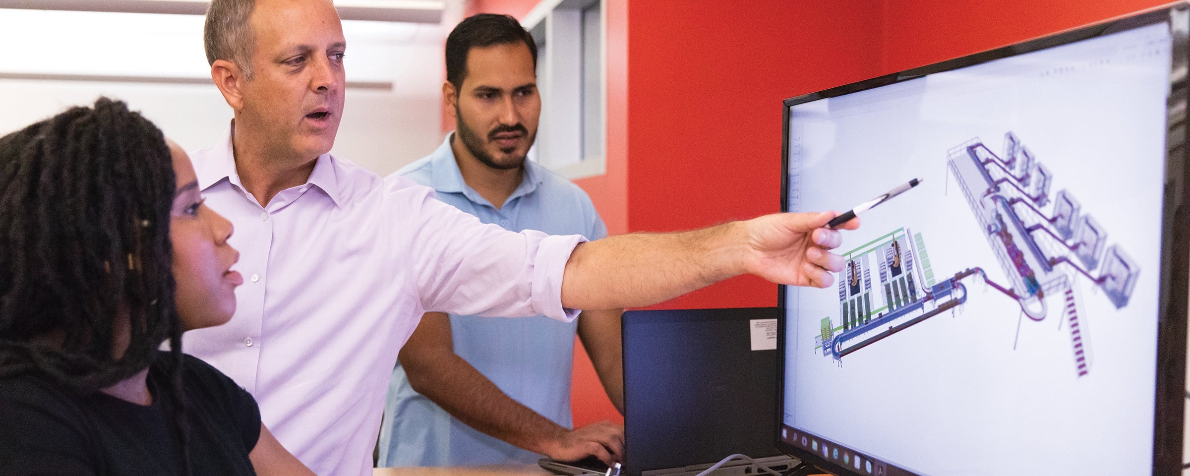 Man discussing rendering on screen with two coworkers
