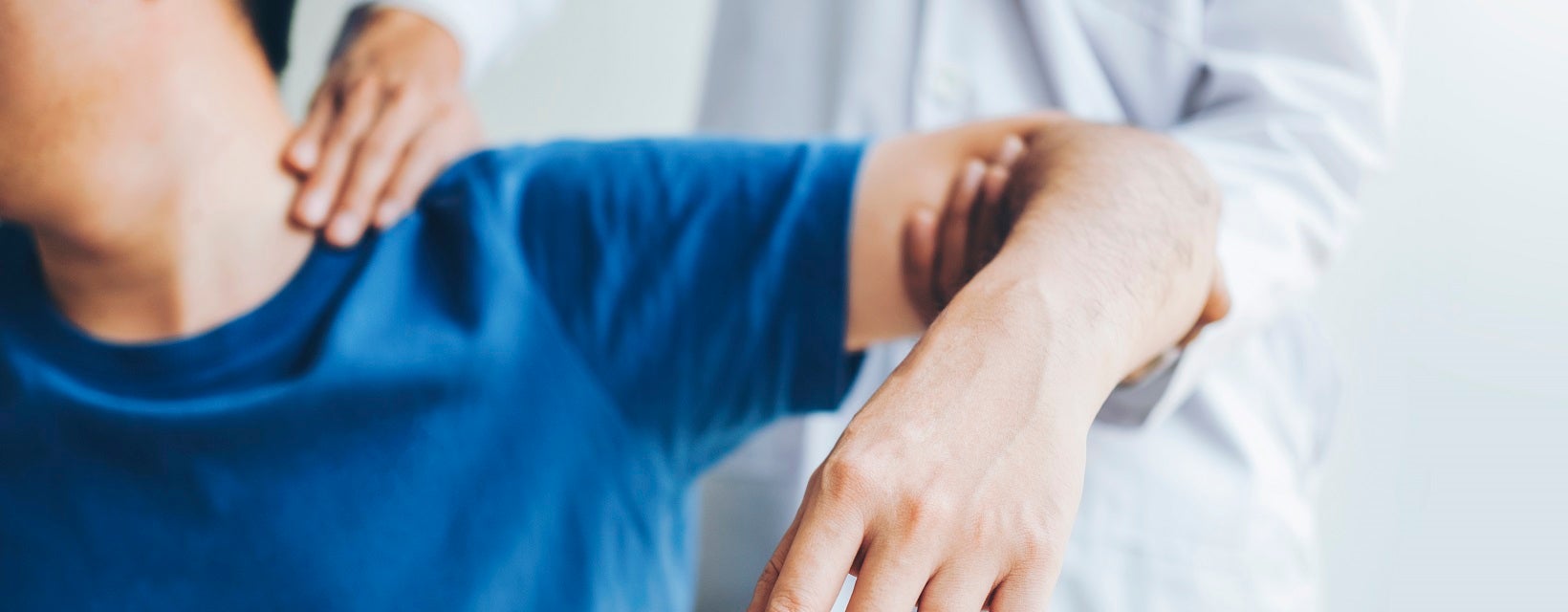 Doctor examining a young man with an injured shoulder