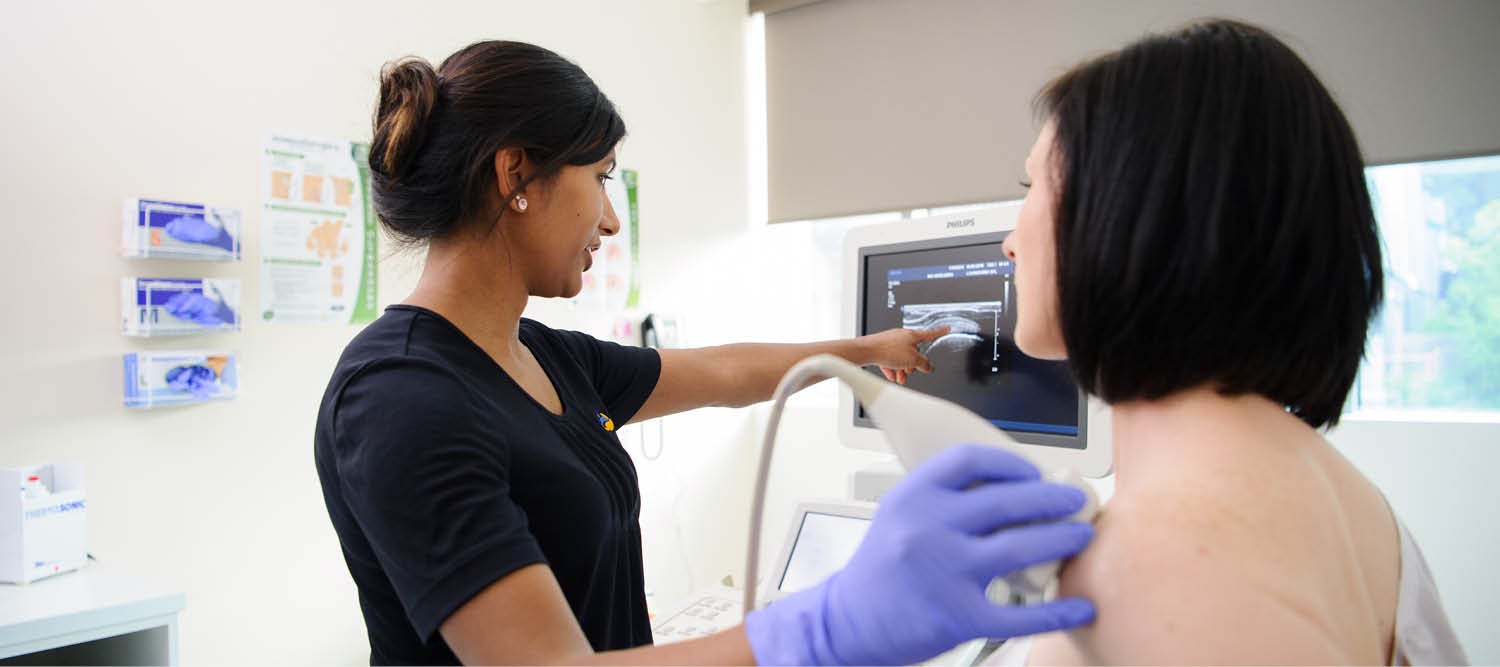 A sonographer scanning a woman's shoulder