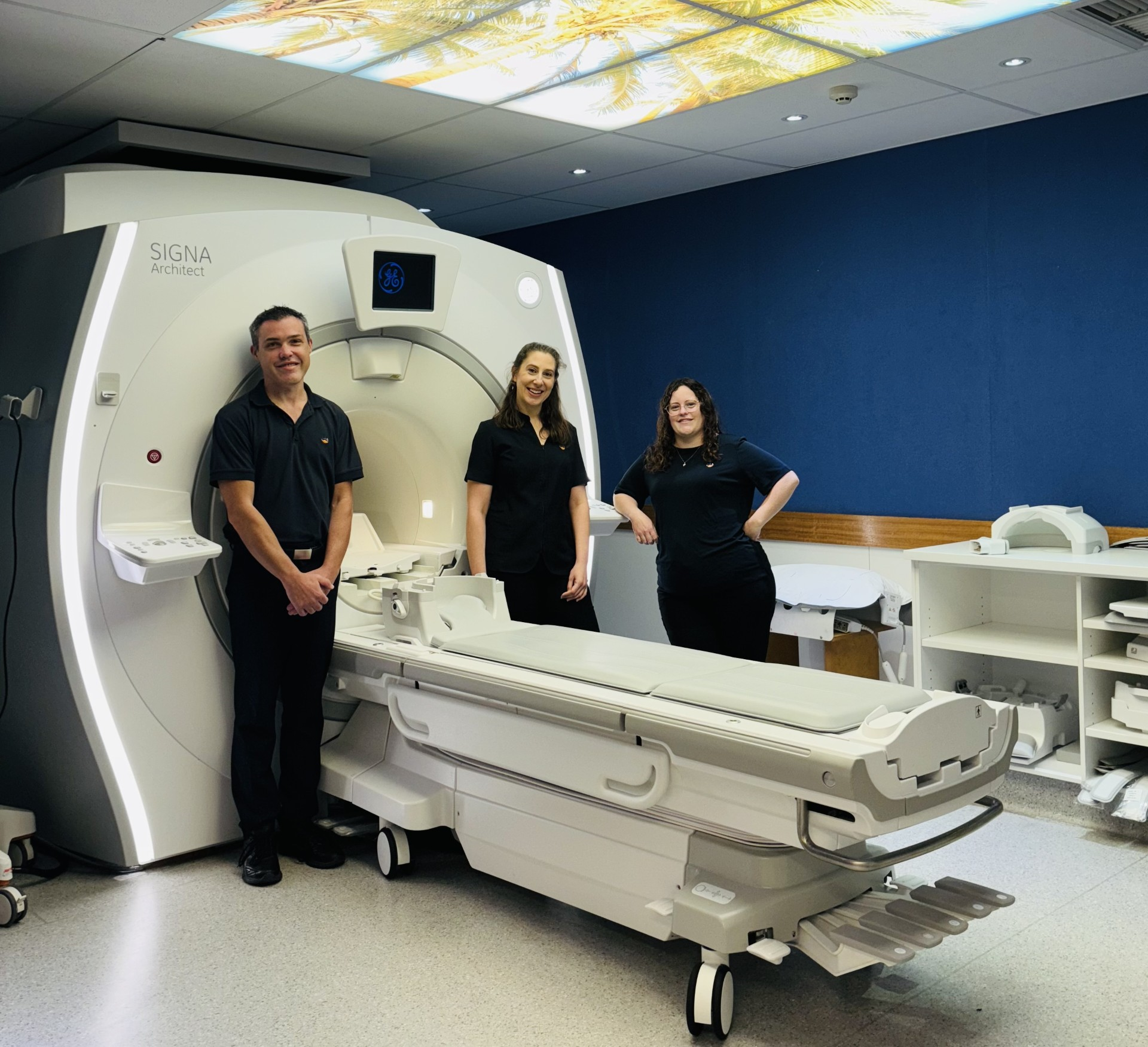 Three I-MED Radiology technicians in front of an MRI machine 