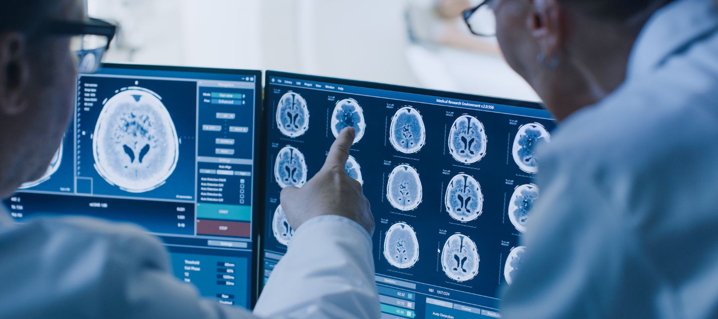 Medical team, radiologist and radiographer looking at CT brain images on screen