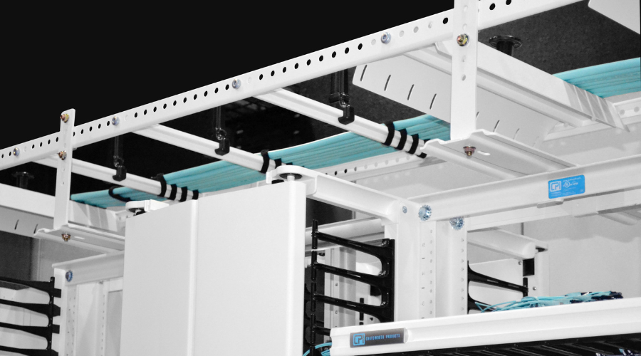 Overhead cable management system with neatly organized blue cables secured in a white cable runway.