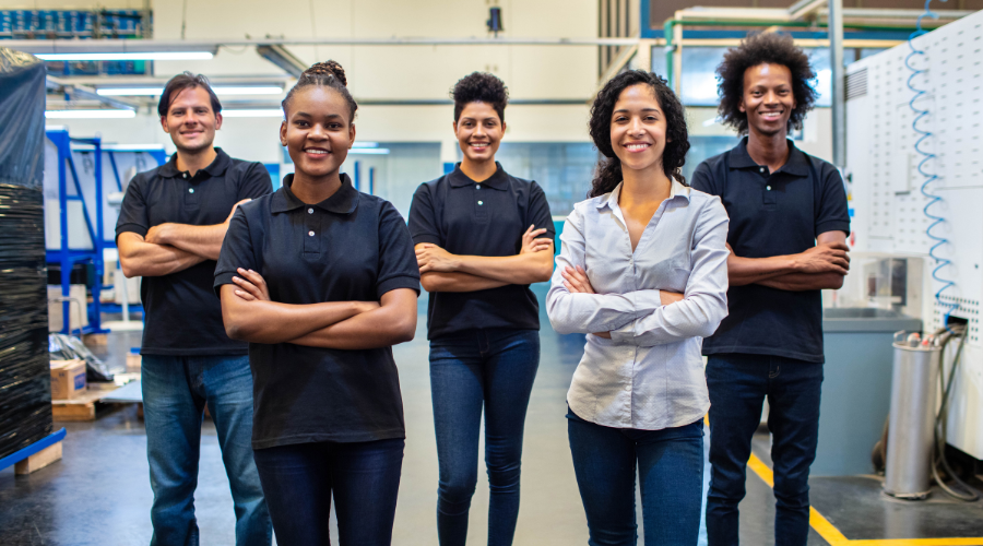 Group of confident employees standing together in a manufacturing facility.