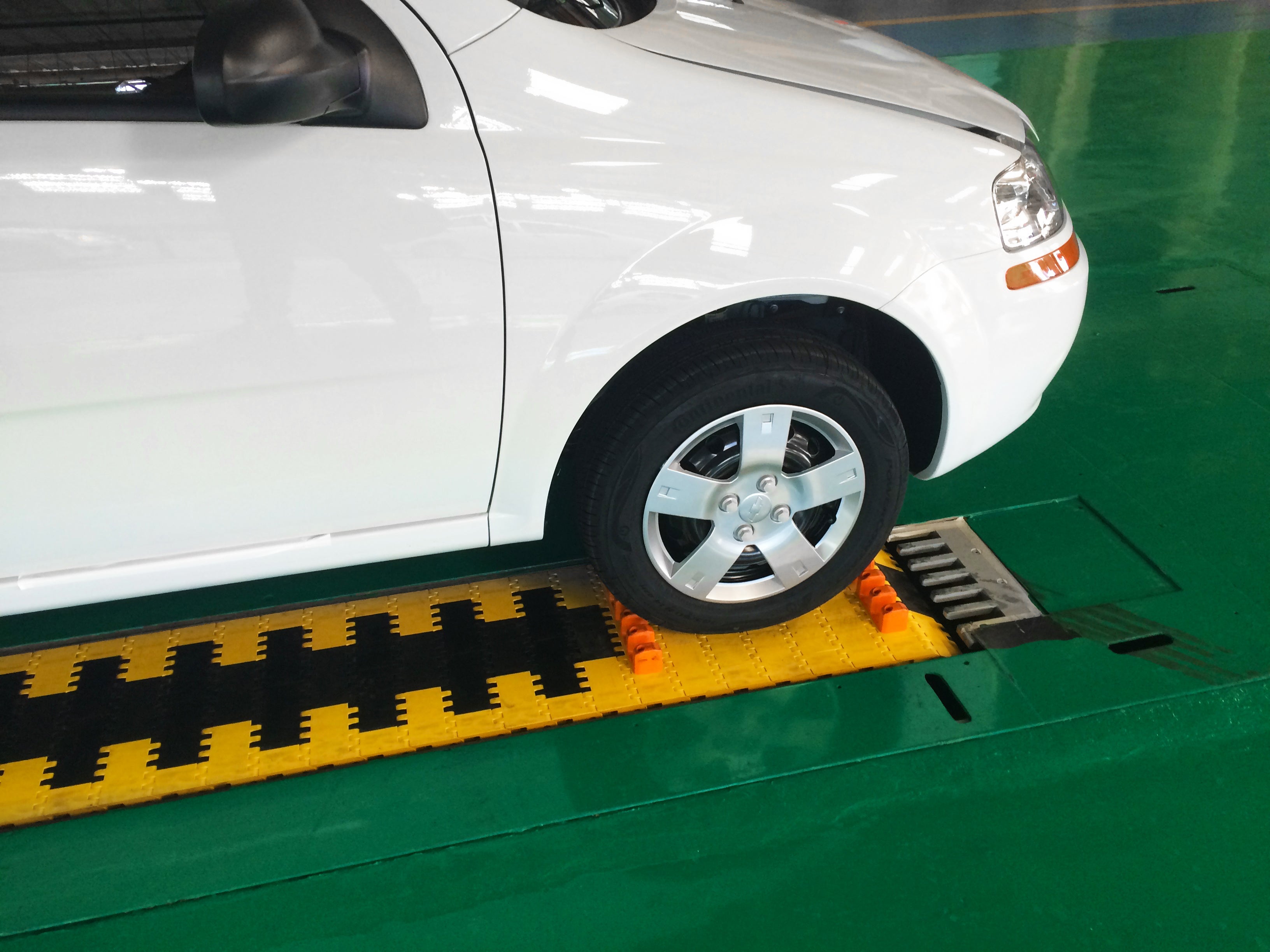 Coche blanco con neumático delantero derecho en la banda transportadora de la serie 10000