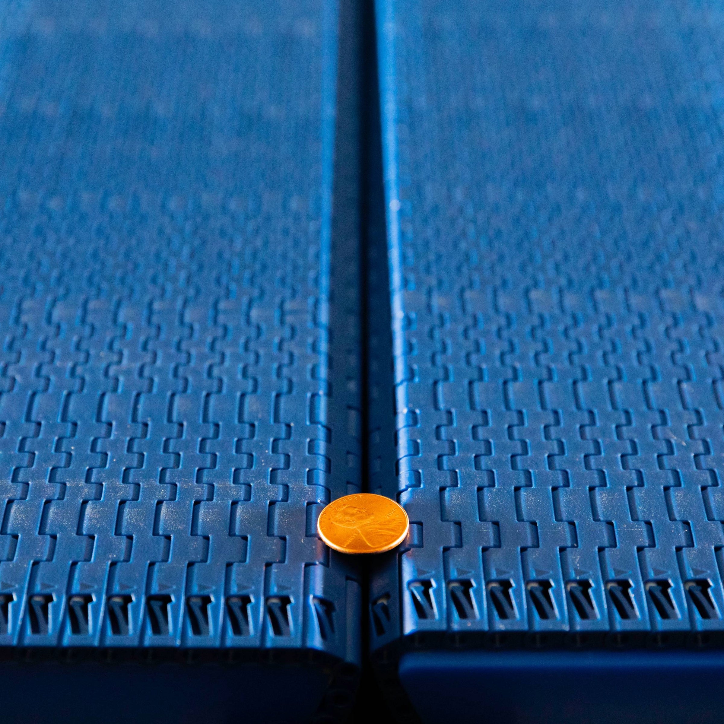 Moneta o nominale jednego pensa, która przechodzi przez lukę transferową pomiędzy dwiema taśmami Flat Top z serii 570