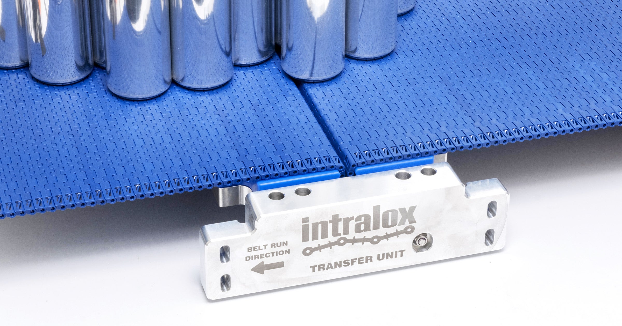 Cans being conveyed on Intralox S570 belting tight transfer with a nosebar.