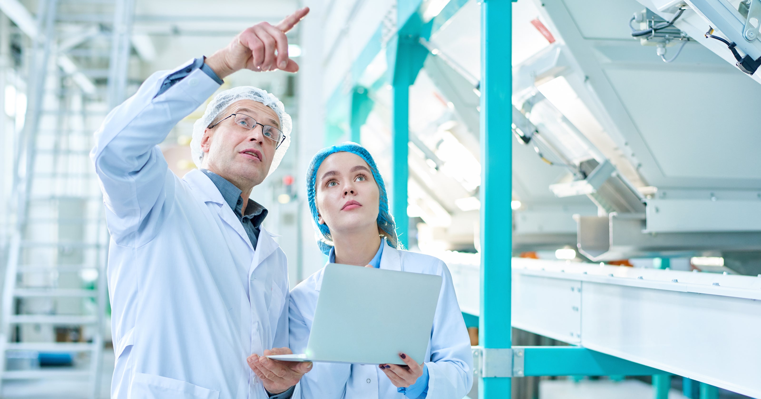 Dois funcionários de segurança dos alimentos realizando inspeção de equipamento em uma fábrica