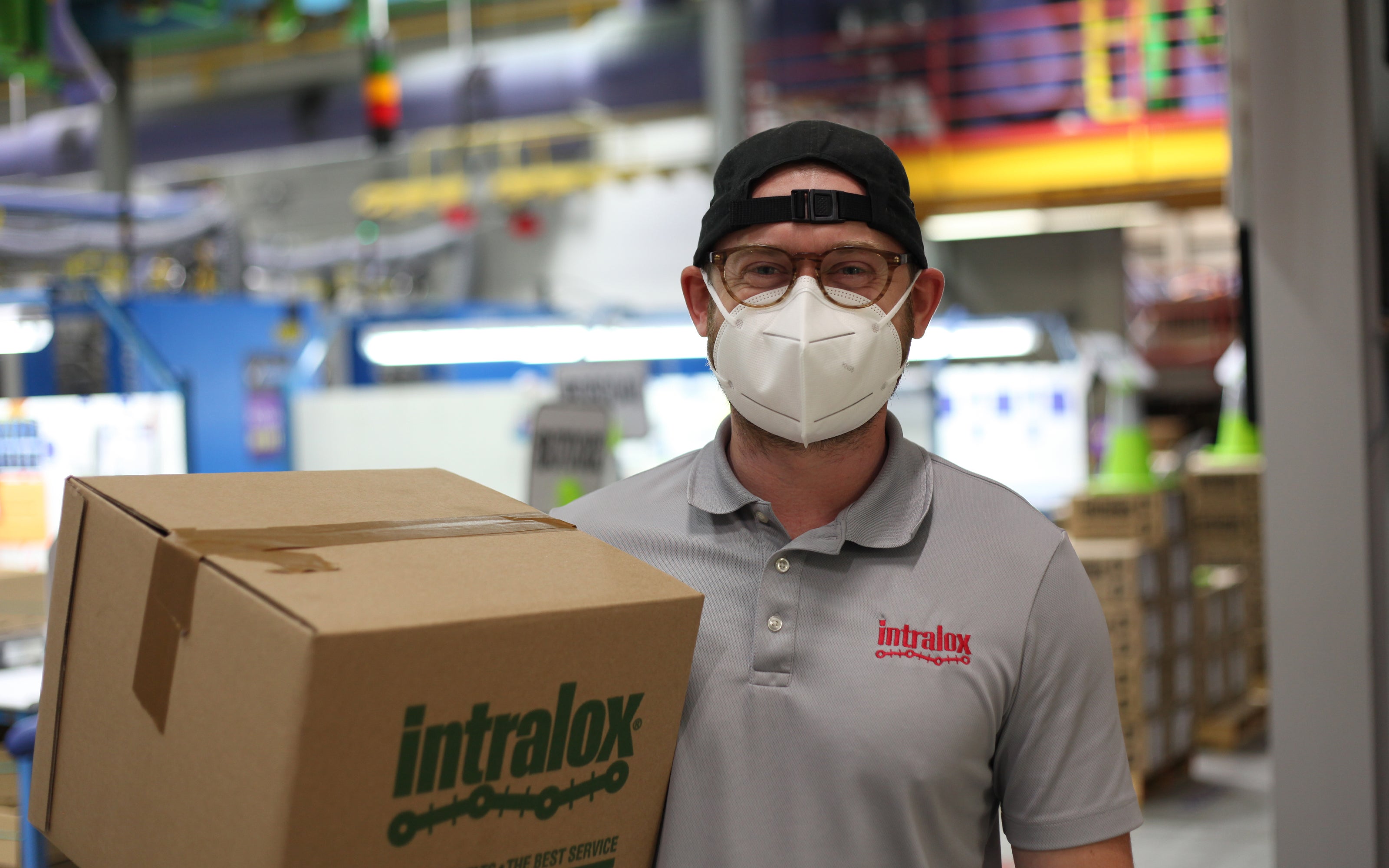 Empleado con mascarilla en un entorno de fase final de línea con paquete