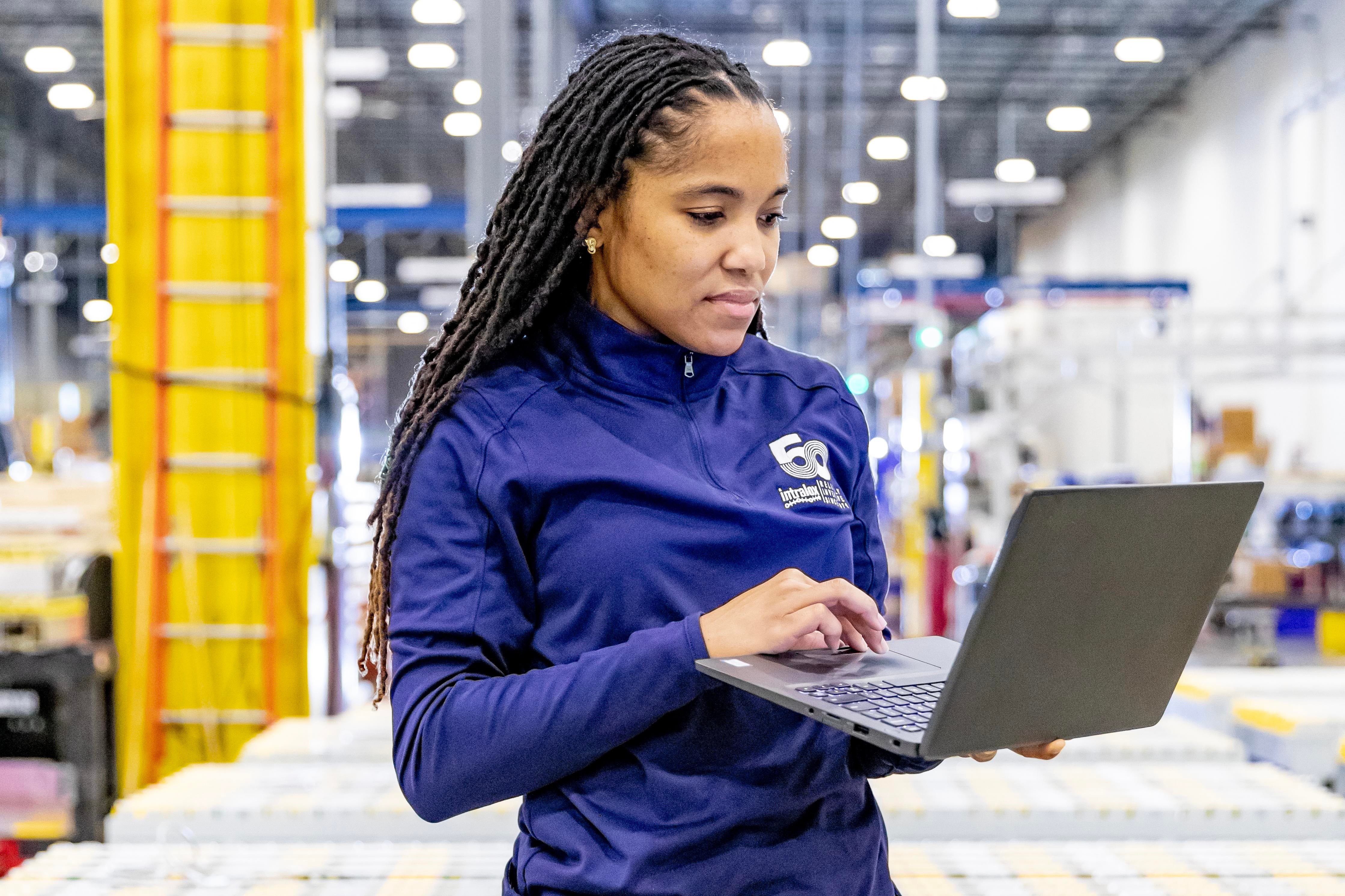 仓库中手握笔记本电脑的女装配工