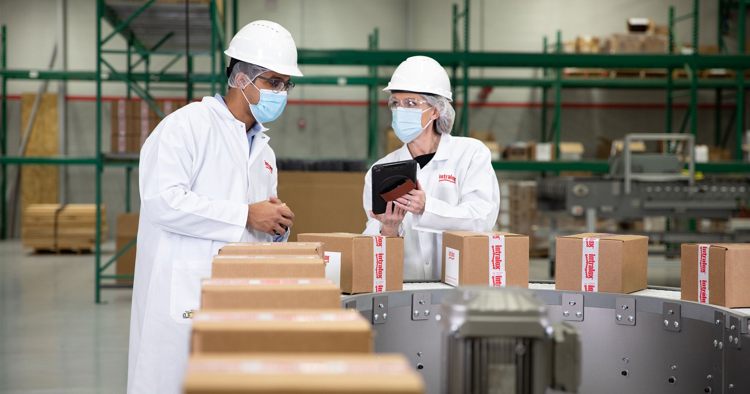 Workers in masks and white coats on packaging line