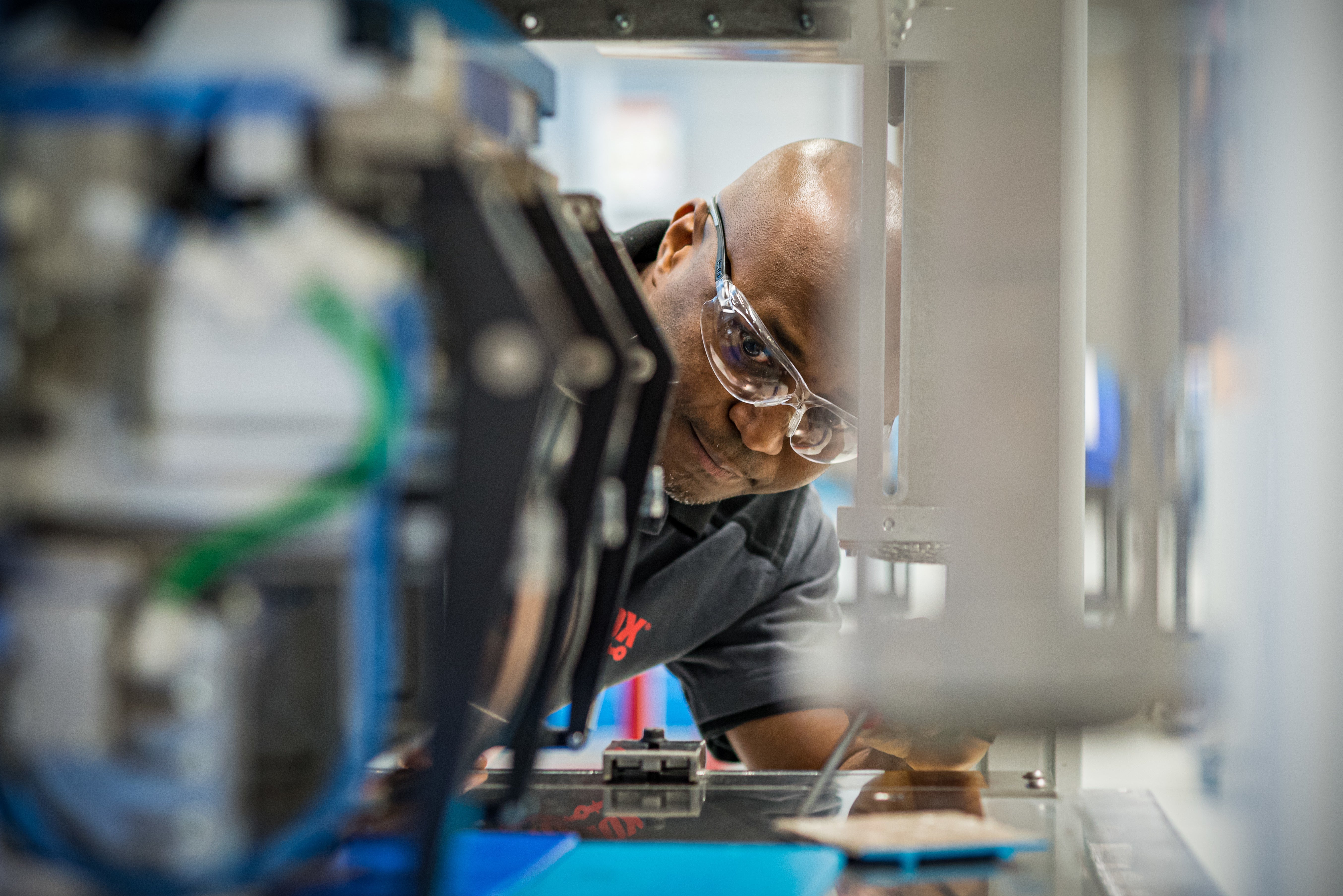 Hombre con gafas de seguridad mirando a la máquina de fabricación del transportador