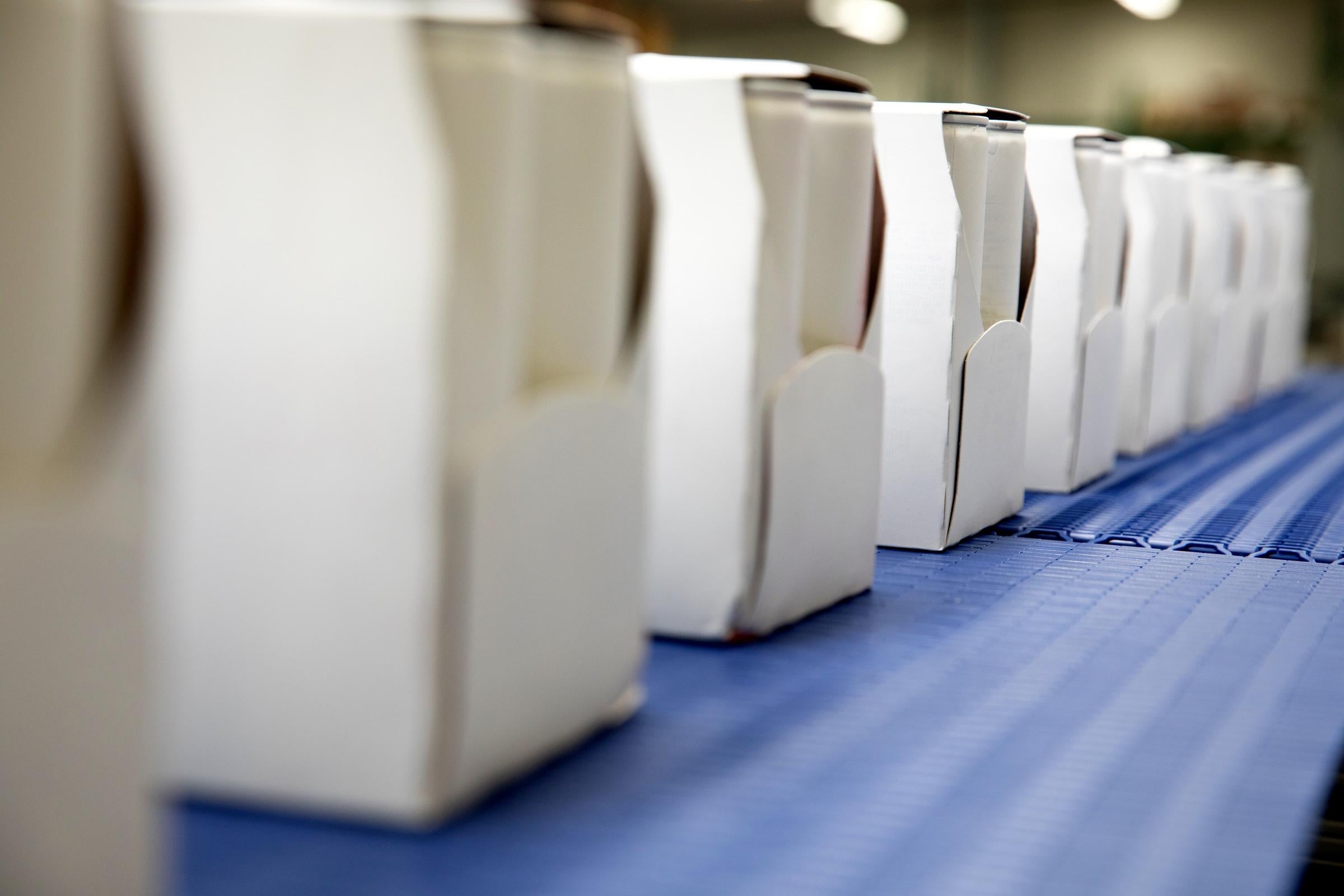 Fila de cajas ligeras blancas en transportadores azules