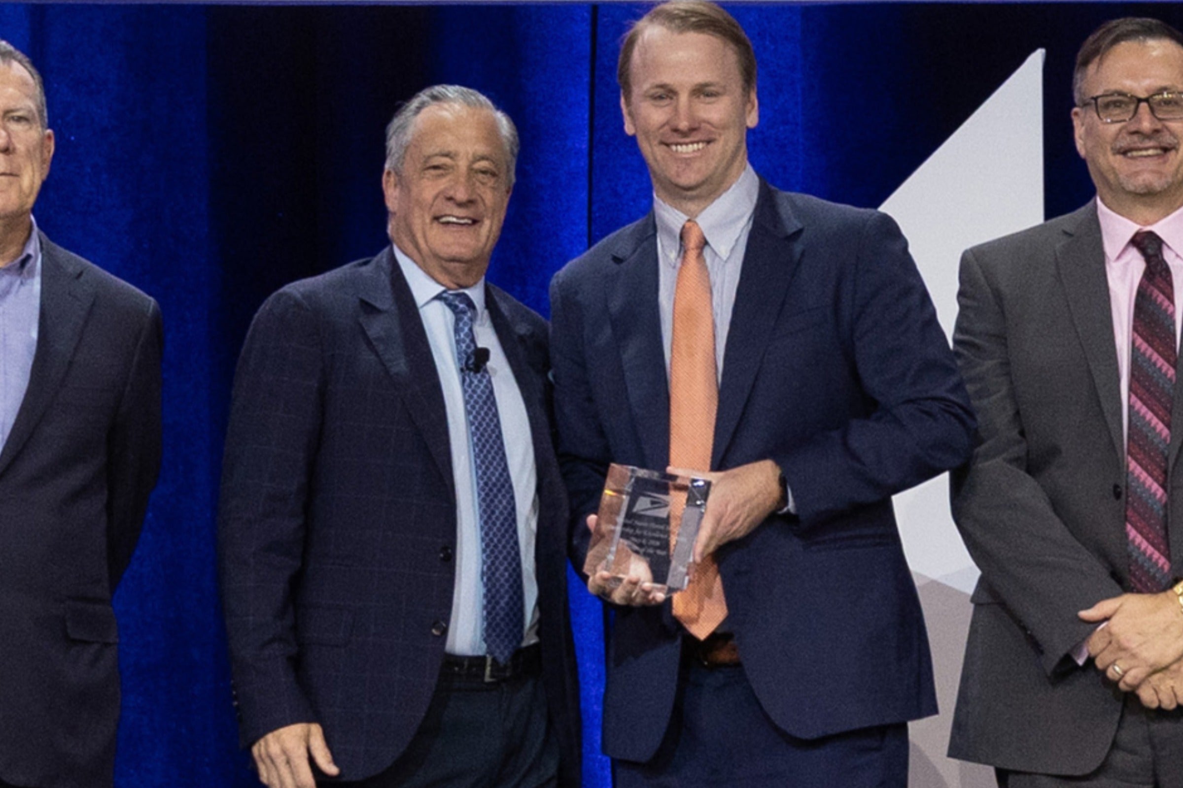 Two men in suits holding award while posing for photograph