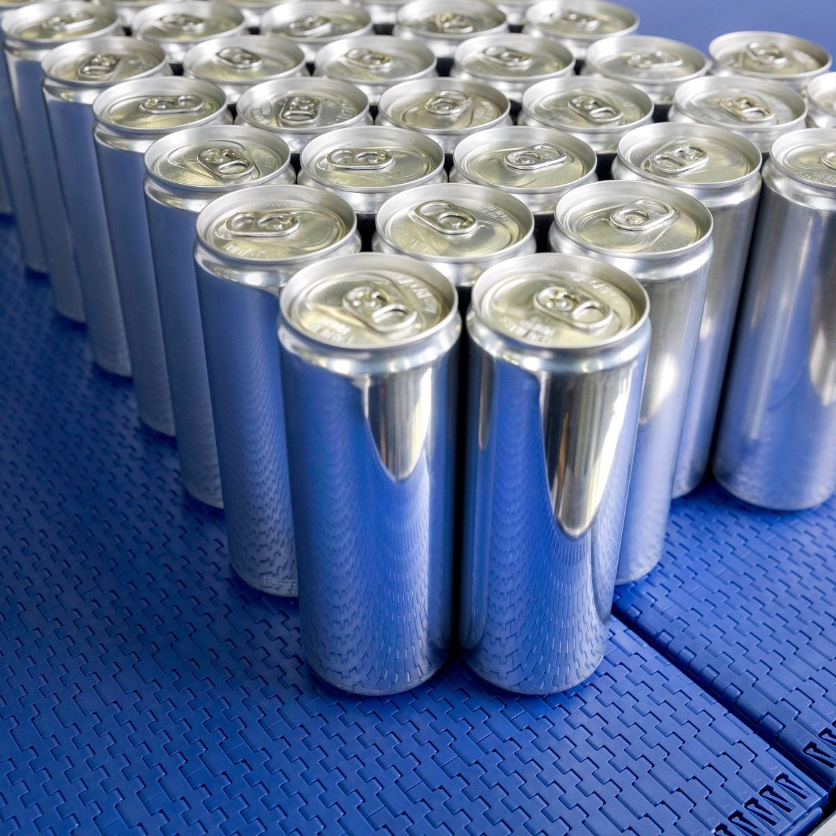 Unlabeled aluminum drinking cans on Intralox Series 570 conveyor belt