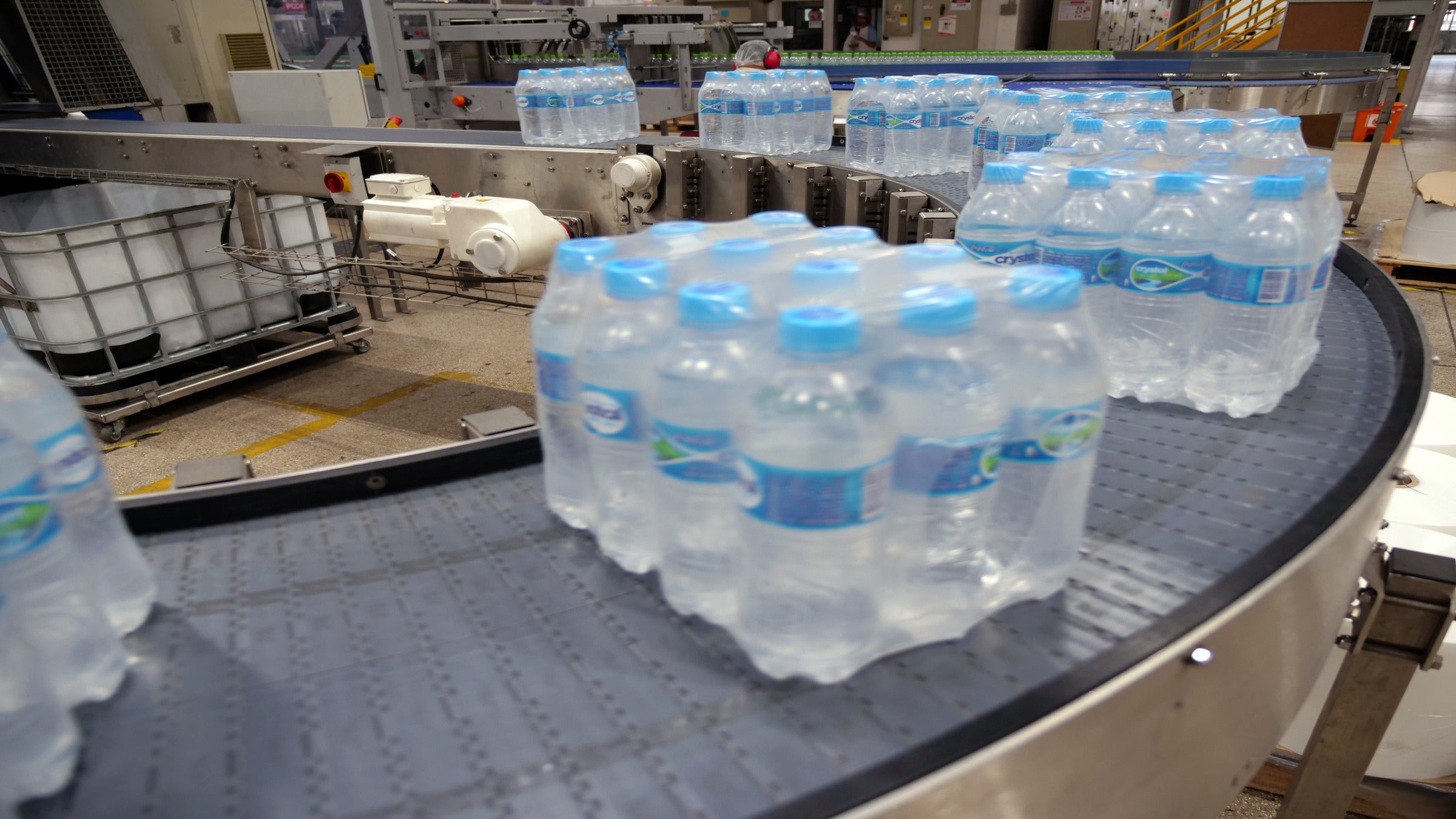 Fasci avvolti in pellicola termoretraibile di trasportatori curvilinei con acqua in bottiglia