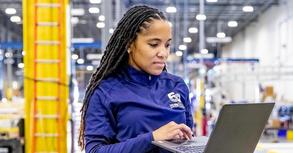 Female assembly worker holding laptop in warehouse