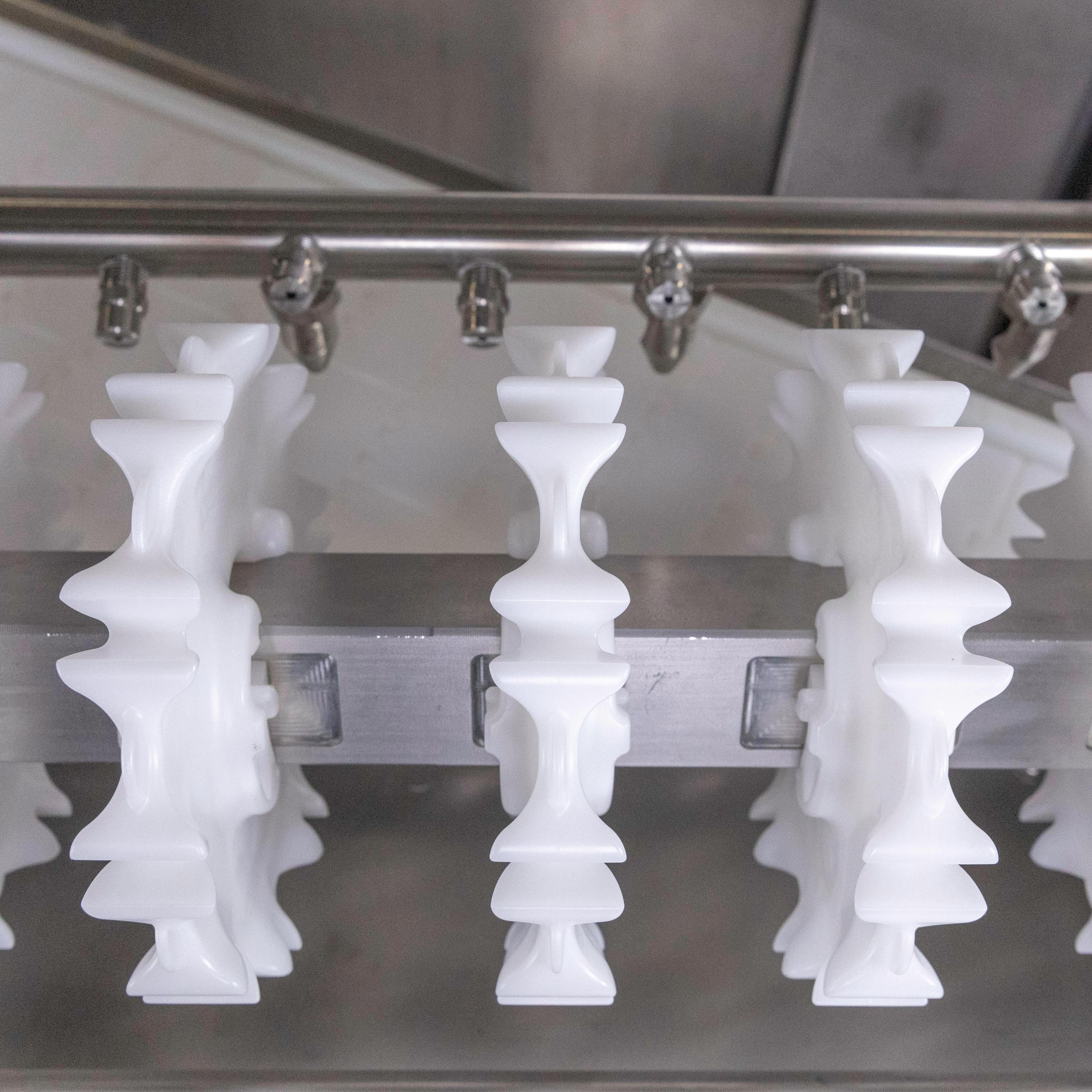 Trzy białe koła zębate CleanLock na wale z drążkiem natryskowym Clean-In-Place