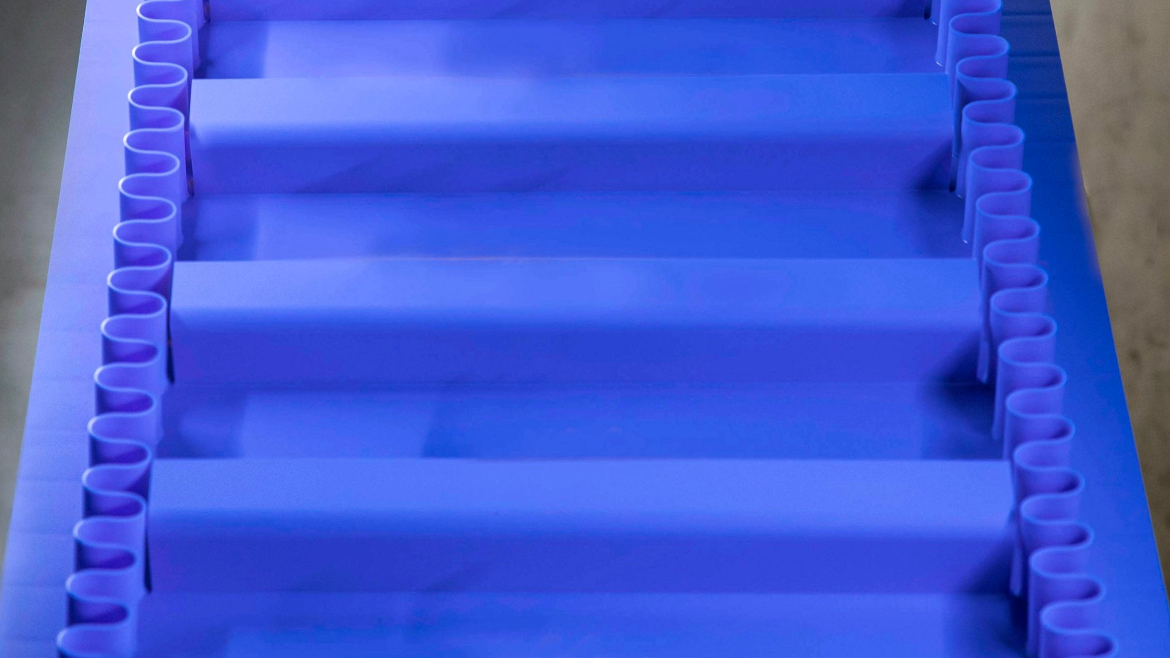 Intralox ThermoDrive-Aufwärtsförderband in A23-Material mit schaufelförmigen Mitnehmern und synchronisierten Seitenwänden