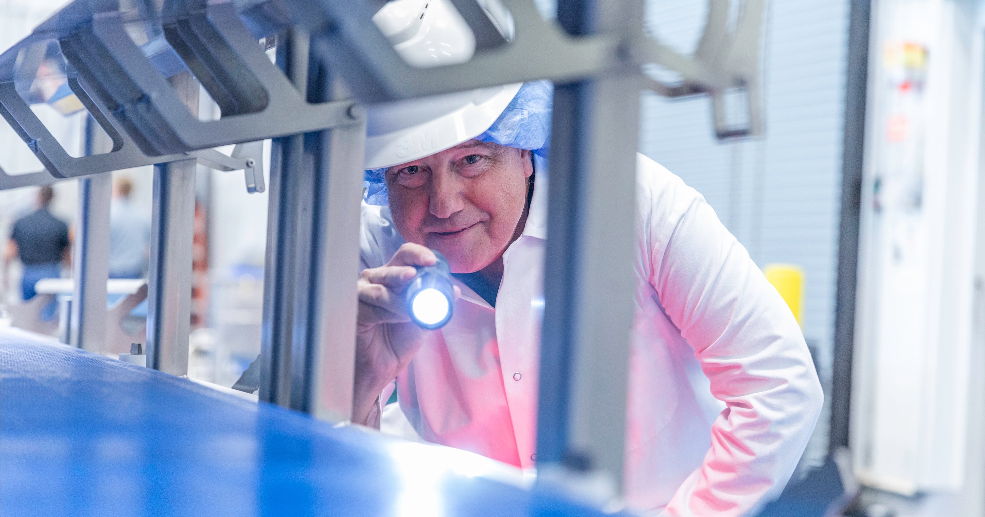 Mężczyzna pochylający się do przodu, aby sprawdzić taśmę za pomocą latarki