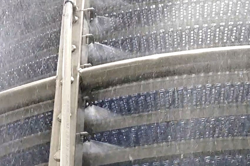 Spirale de refroidissement hydraulique avec projection d'eau sur un tapis transporteur