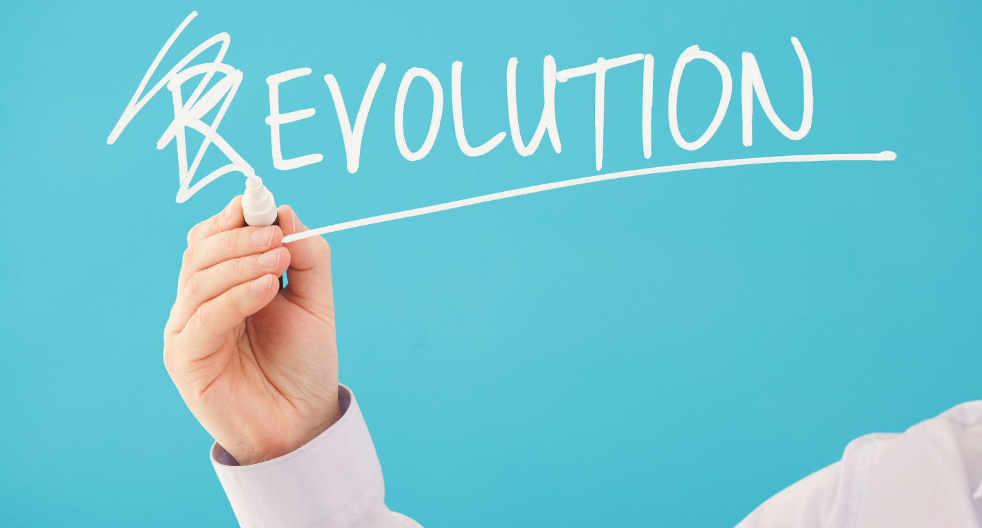 Hand writing the word Revolution on a blue board and crossing out the letter R to make it read as Evolution.