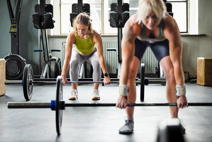 Two women at the gym exercising with weights