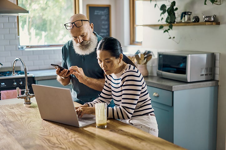 A couple using a laptop and a mobile phone