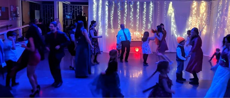 Dancing guests in the dimly lit hall with the ritual table candles in the background.