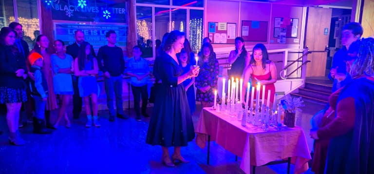 Guests stand in a wide circle as candles are lit during the Imbolc ritual.