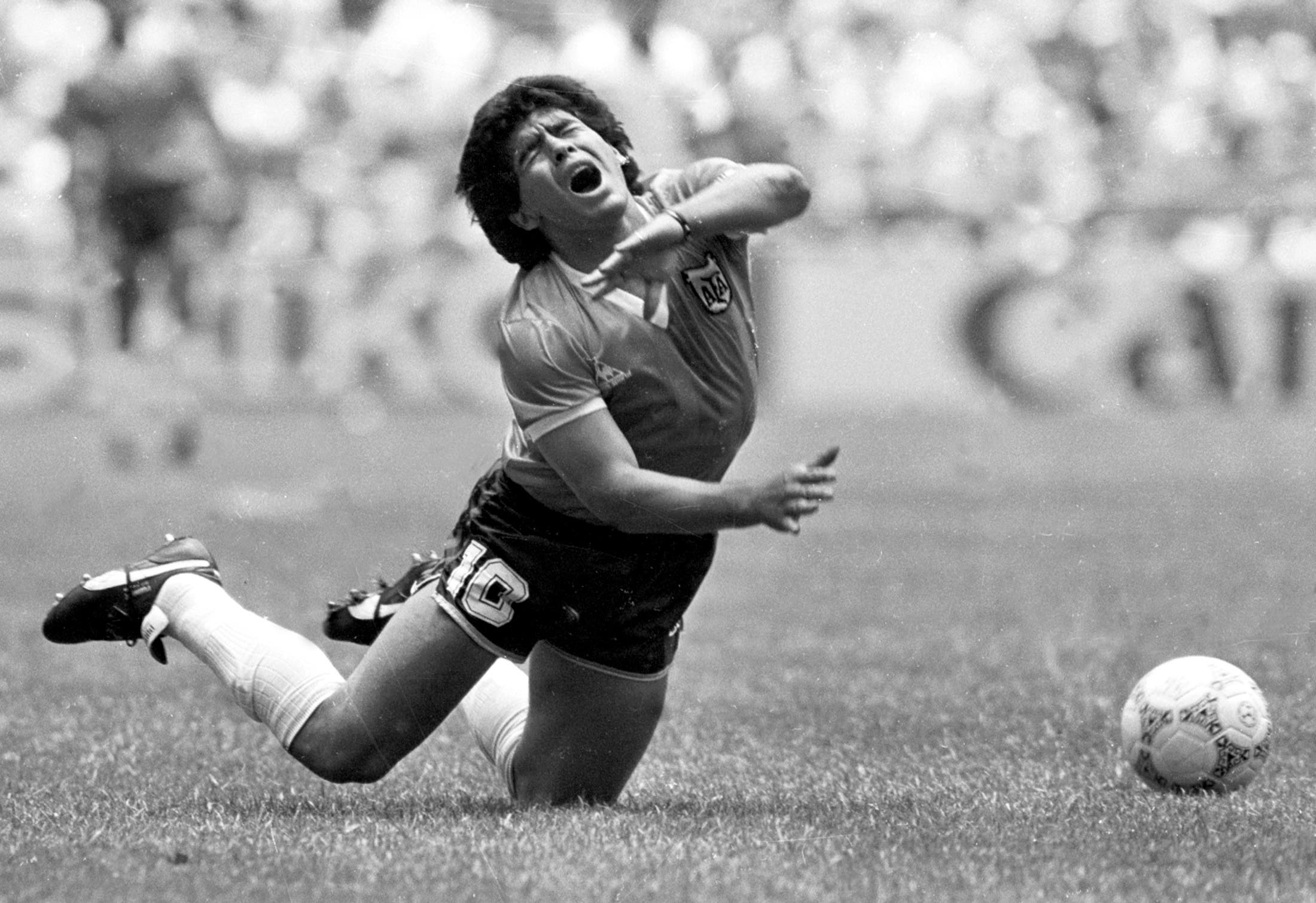 Argentina's Diego Maradona falls to the pitch after being tripped up in their World Cup quarterfinal match against England in Mexico City in this June 22, 1986 file photo. Maradona scored both goals in Argentina's 2-1 victory. Maradona remained in intensive care on Tuesday morning, more than 36 hours after falling ill with heart and breathing problems. A clutch of fans continued a vigil outside the posh Buenos Aires clinic where Maradona, one of the most gifted players in soccer history, was rushed on Sunday. Maradona arrived at the clinic in a serious, feverish condition with breathing difficulties and a swollen heart after watching a game at his former club Boca Juniors' stadium where he made his name. (B/W ONLY) REUTERS/Gary Hershorn GMH

