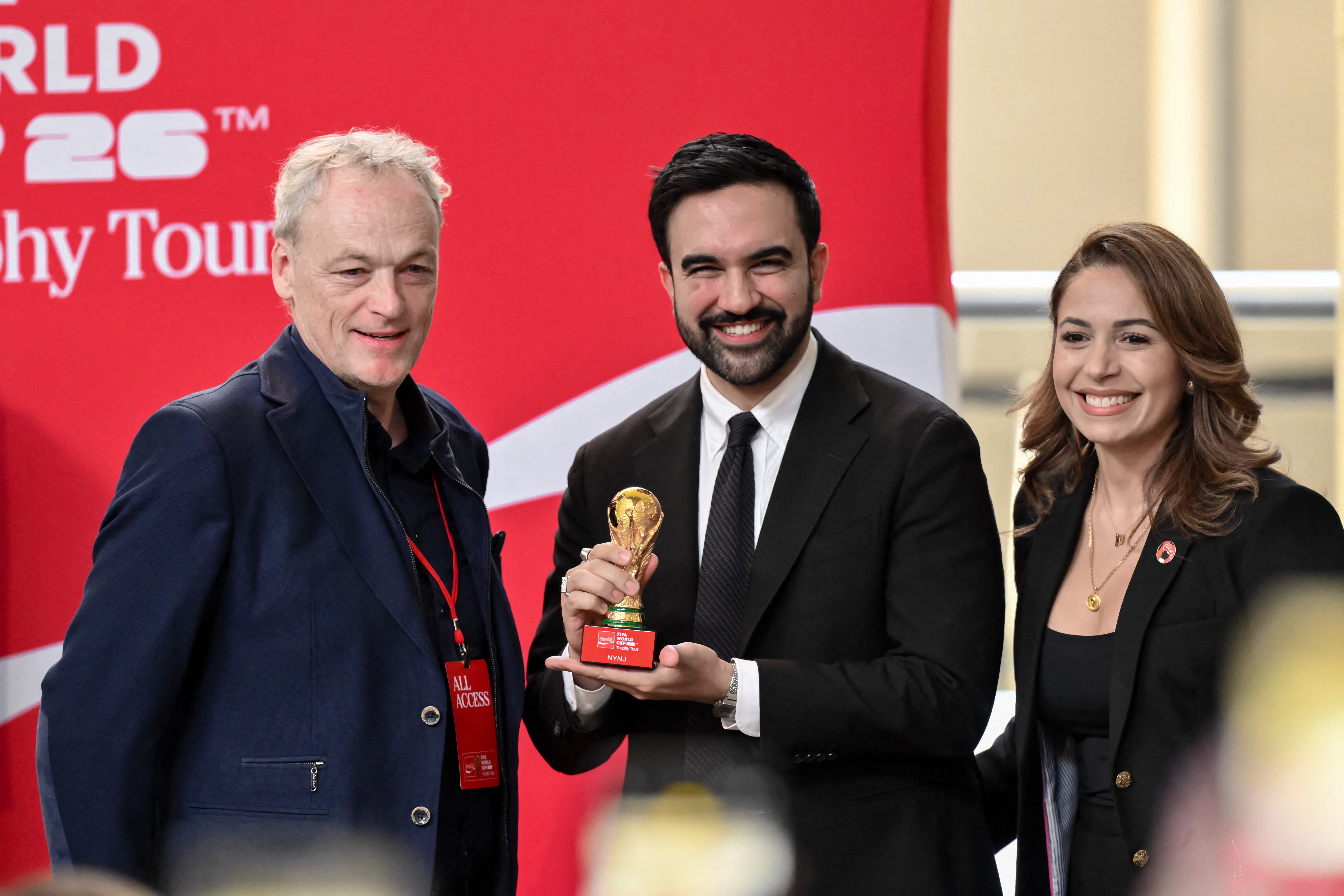 Jun 2, 2026; New York, New York, USA; New York City mayor Zohran Mamdani (center) poses with a replica trophy with Paul Mulligan, President of Coca-Cola Refreshments, and Mayra Linares-Garcia, Vice President, Public Affairs and Communications at Liberty Coca-Cola Beverages during an event for the FIFA World Cup Trophy Tour at American Museum of Natural History. Mandatory Credit: John Jones-Imagn Images