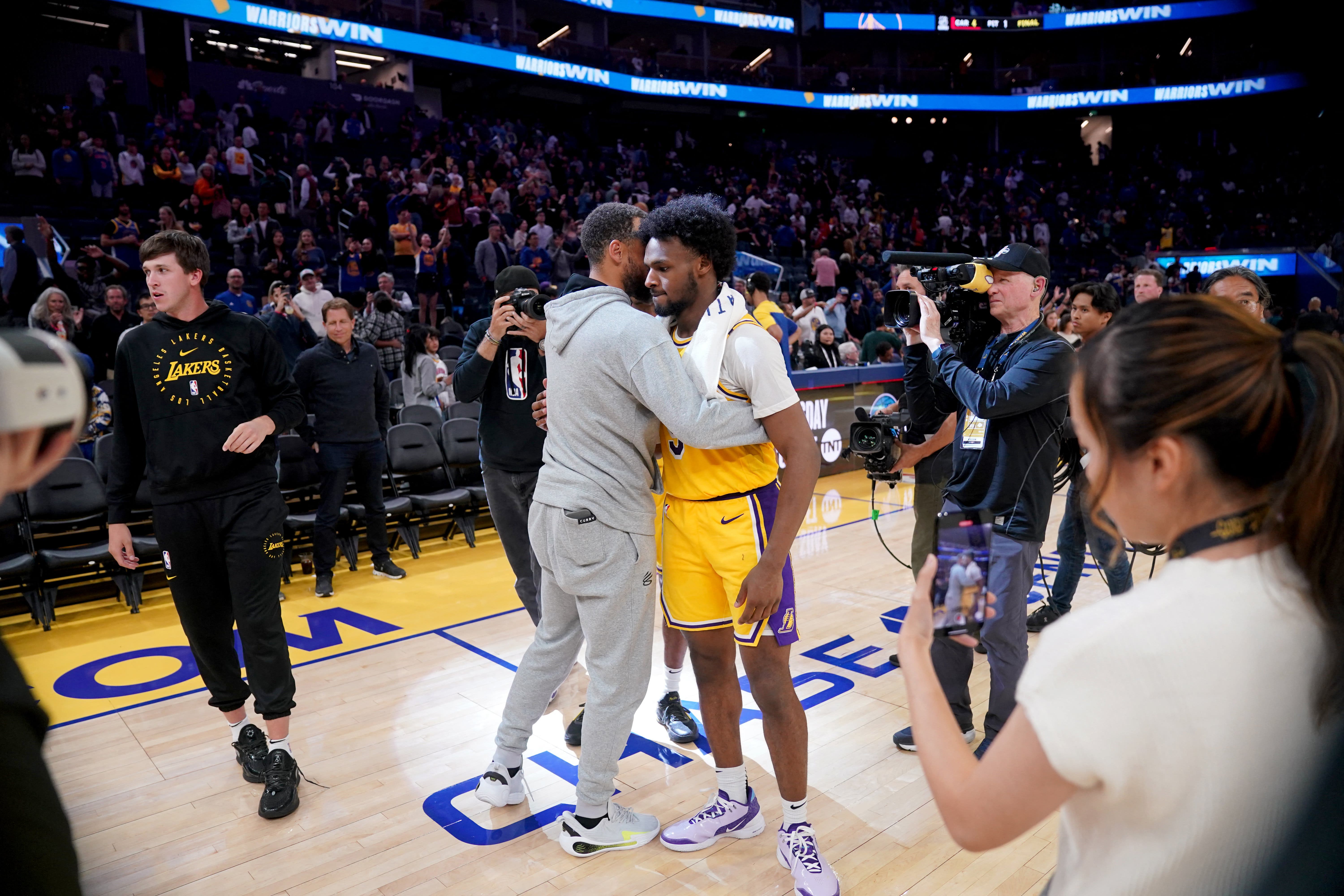 Bronny James and Stephen Curry greeting each other at an NBA event.