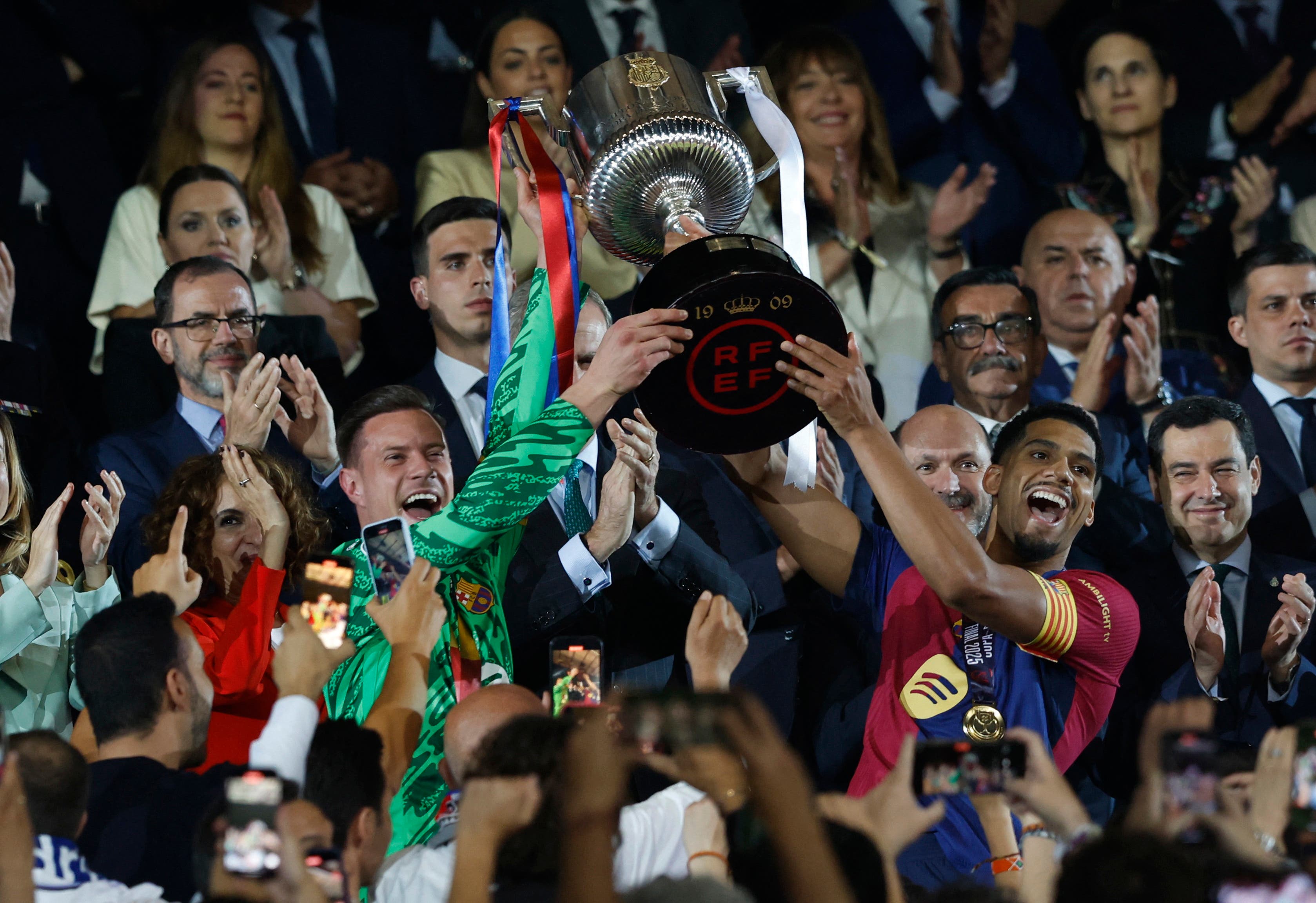 Soccer Football - Copa del Rey - Final - FC Barcelona v Real Madrid - Estadio de La Cartuja, Seville, Spain - April 26, 2025 FC Barcelona's Marc-Andre ter Stegen and Ronald Araujo receive the trophy after winning the Copa del Rey REUTERS/Marcelo Del Pozo