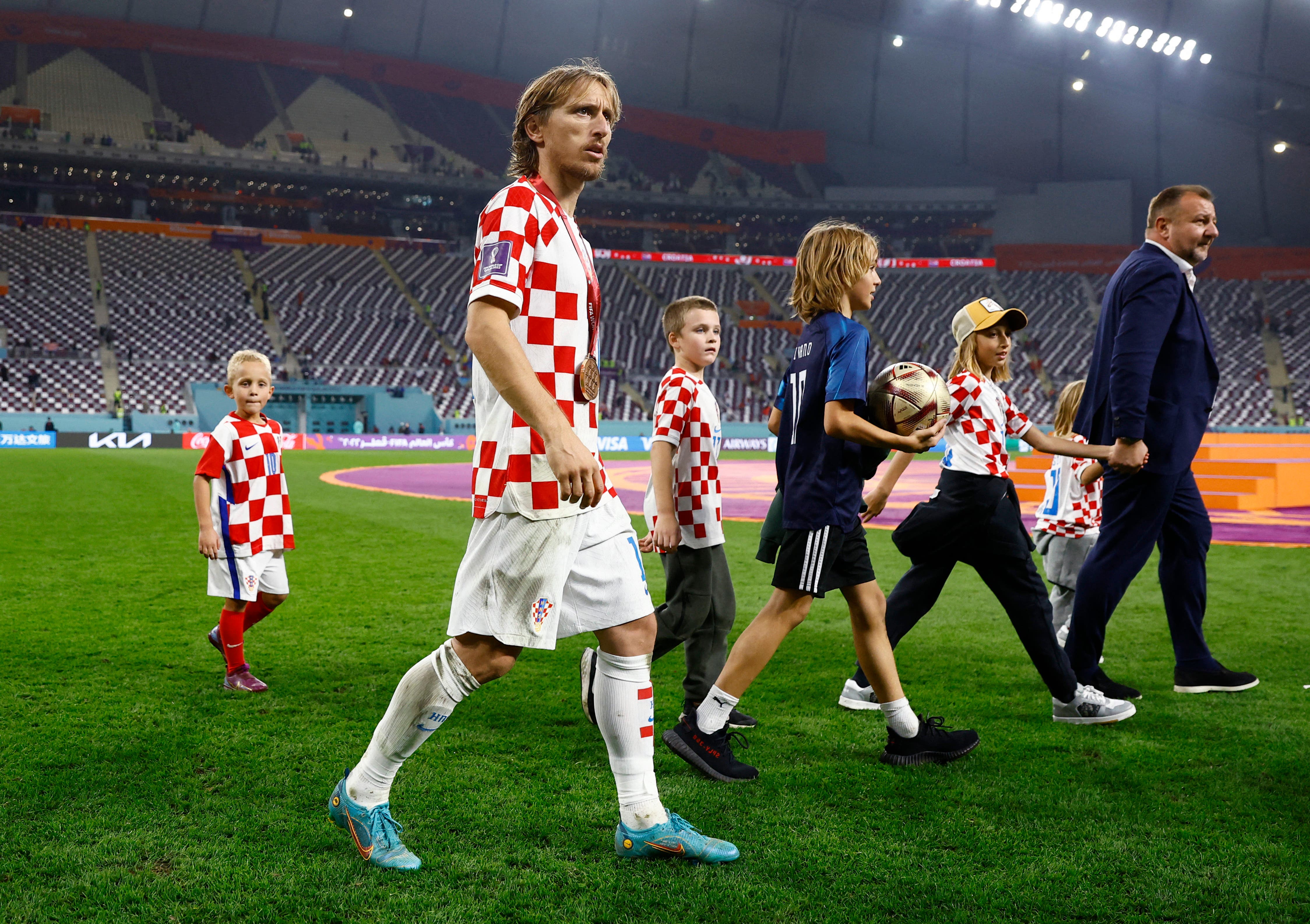 Soccer Football - FIFA World Cup Qatar 2022 - Third-Place Playoff - Croatia v Morocco - Khalifa International Stadium, Doha, Qatar - December 17, 2022 Croatia's Luka Modric wears his medal as he celebrates with a child on the pitch after Croatia finish in third place REUTERS/Peter Cziborra