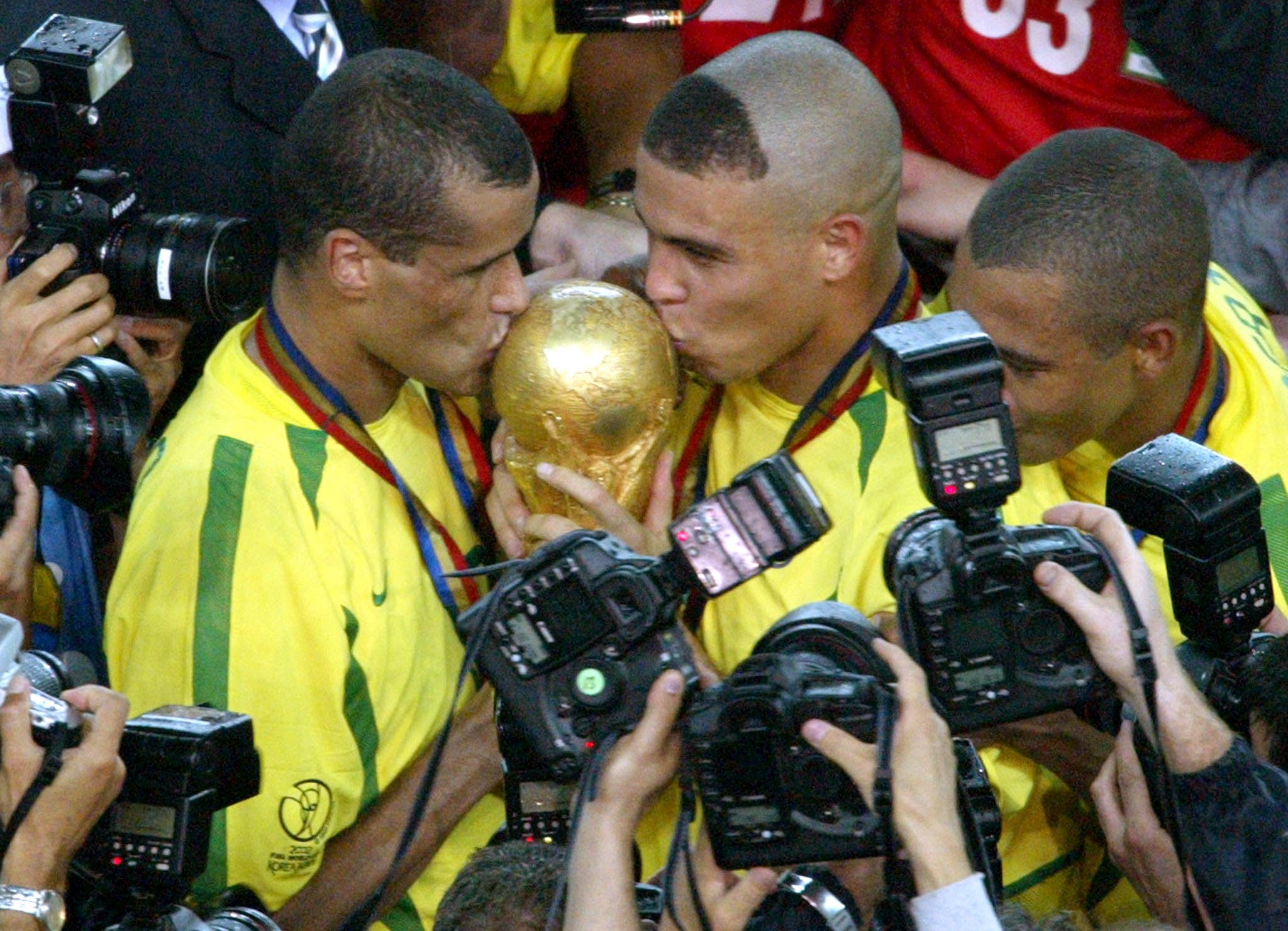 Brazil's Ronaldo (C) and Rivaldo (L) kiss the World Cup trophy as team mate Kleberson (R) joins them after their 2-0 victory over Germany in the World Cup final in Yokohama June 30, 2002. Ronaldo scored both goals. REUTERS/Oleg Popov OP/GB/JD