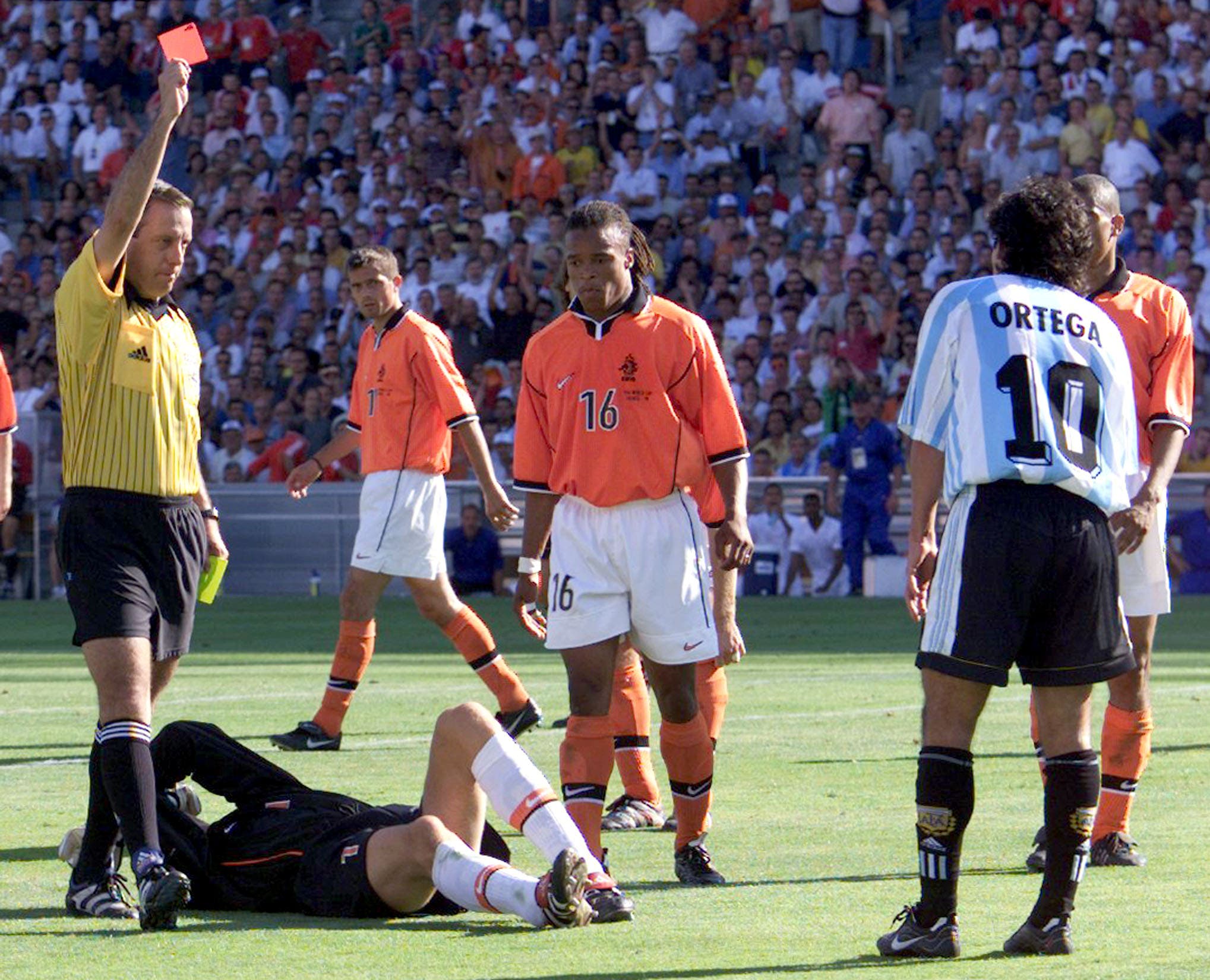 Mexican referee Arturo Brizio Carter shows a red card to Ariel Ortega (R) of Argentina after he headbutted Dutch goalkeeper Edwin Van Der Sar (on the ground) during a quarter final World Cup match July 4. The Netherlands won the match 2-1 and advance to the semi final. TOM/JES/