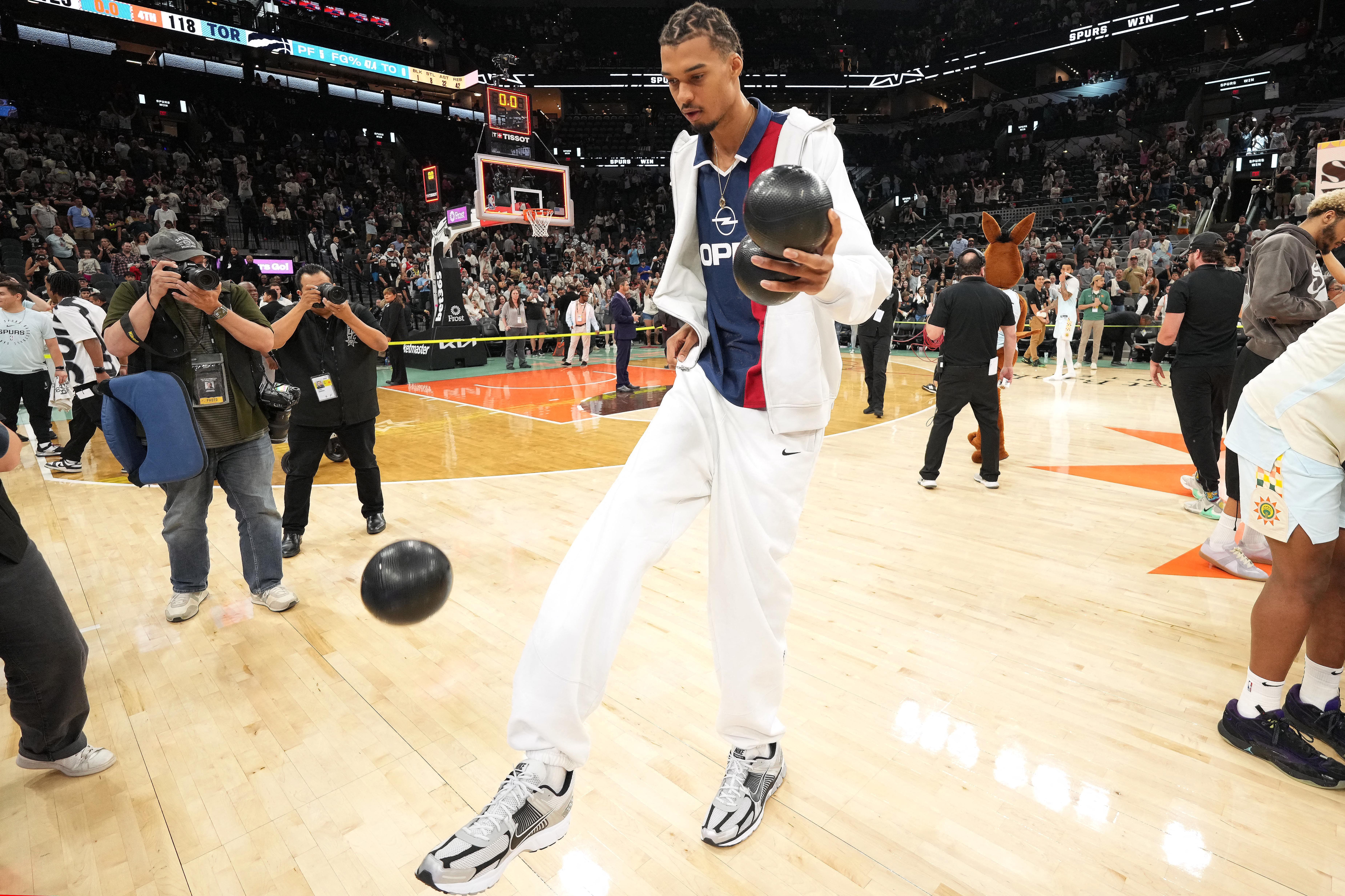 San Antonio Spurs center Victor Wembanyama (1) plays around with a ball in celebration of Fan Appreciation Day after a victory over the Toronto Raptors at Frost Bank Center.