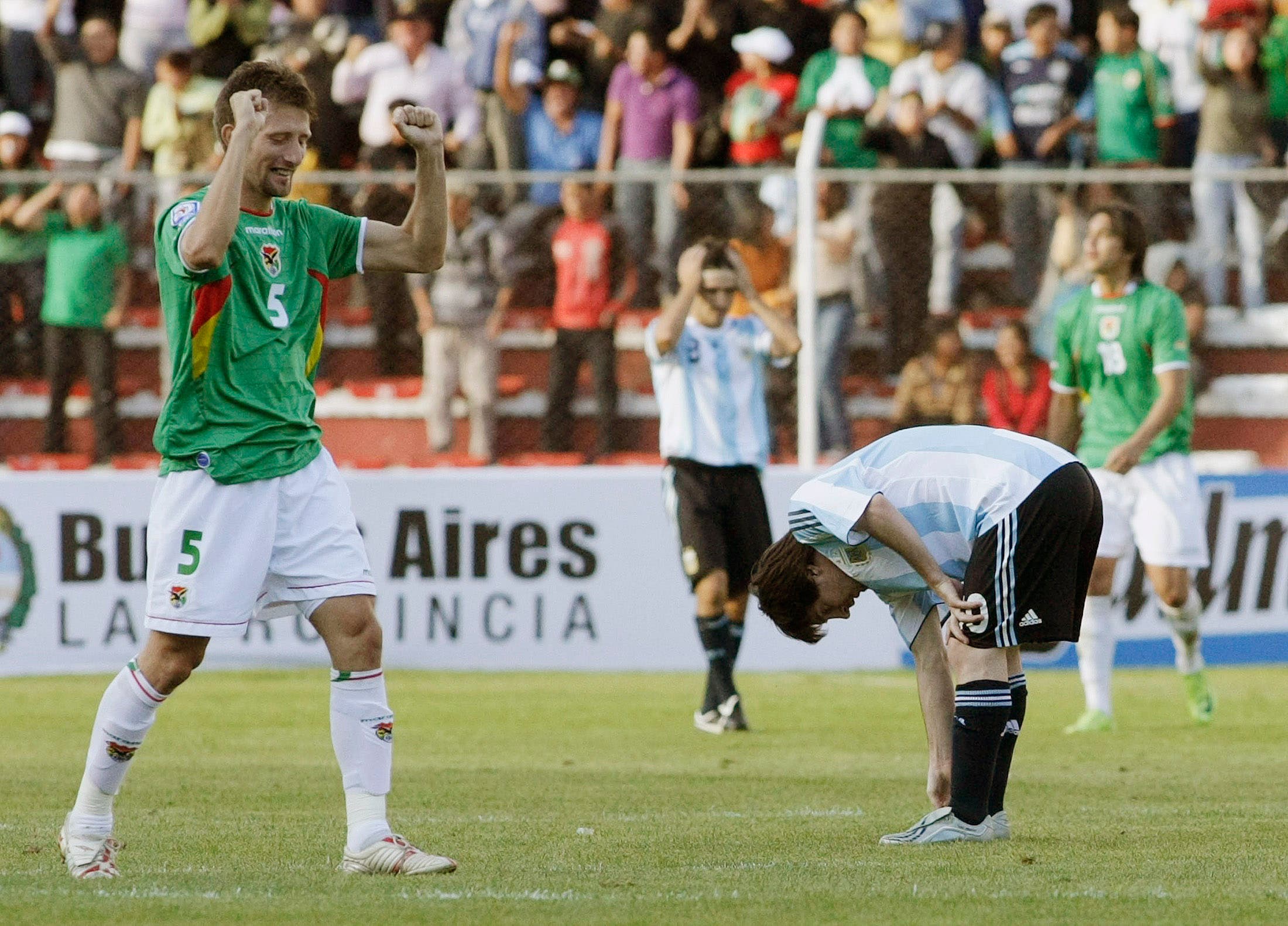 Argentina's Lionel Messi reacts as Bolivia's Ronald Rivero celebrates his team's sixth goal during a 2010 World Cup qualifying soccer match in La Paz