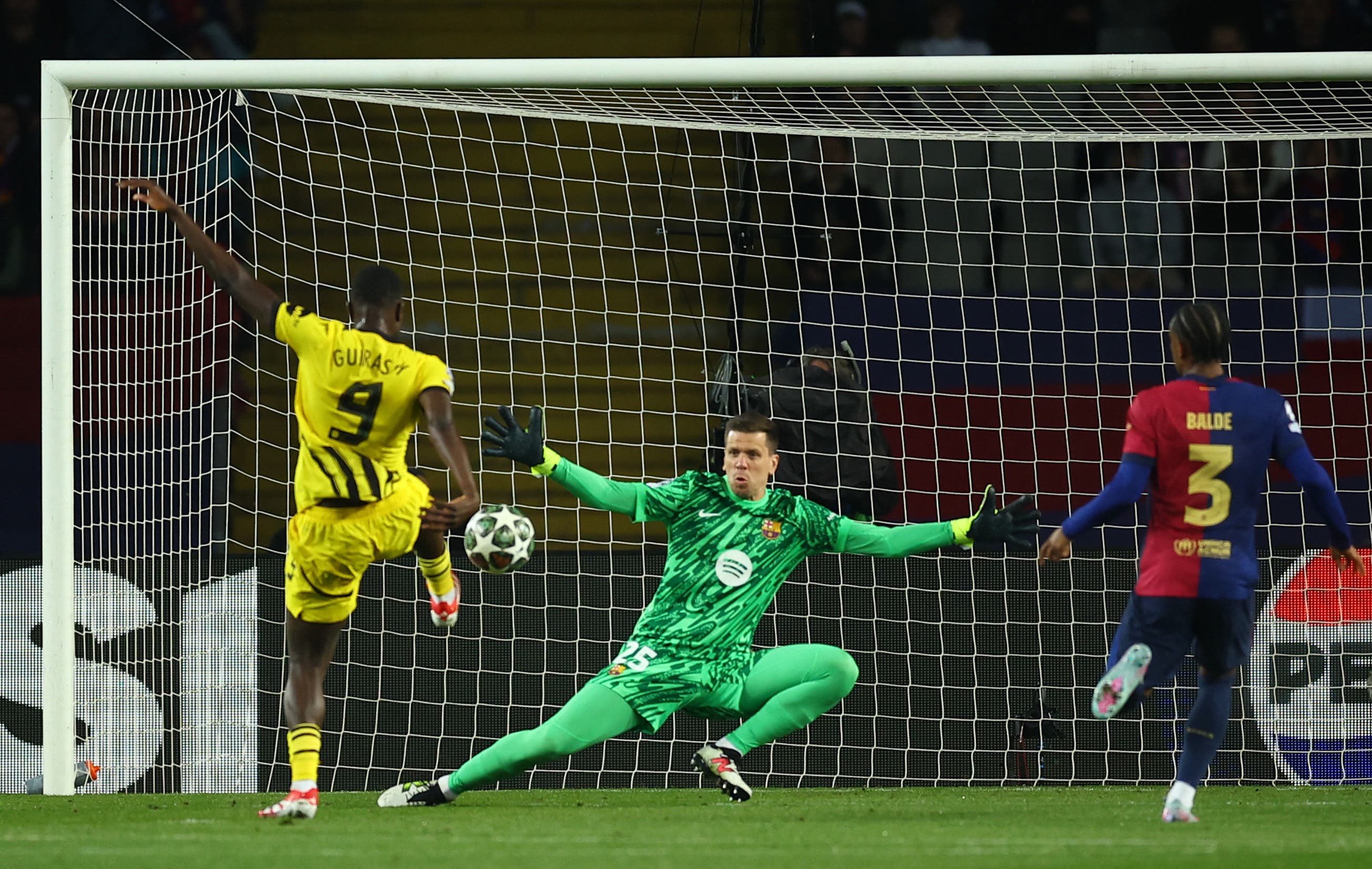 Dortmund's Serhou Guirassy shoots at goal as FC Barcelona's Wojciech Szczesny reacts 