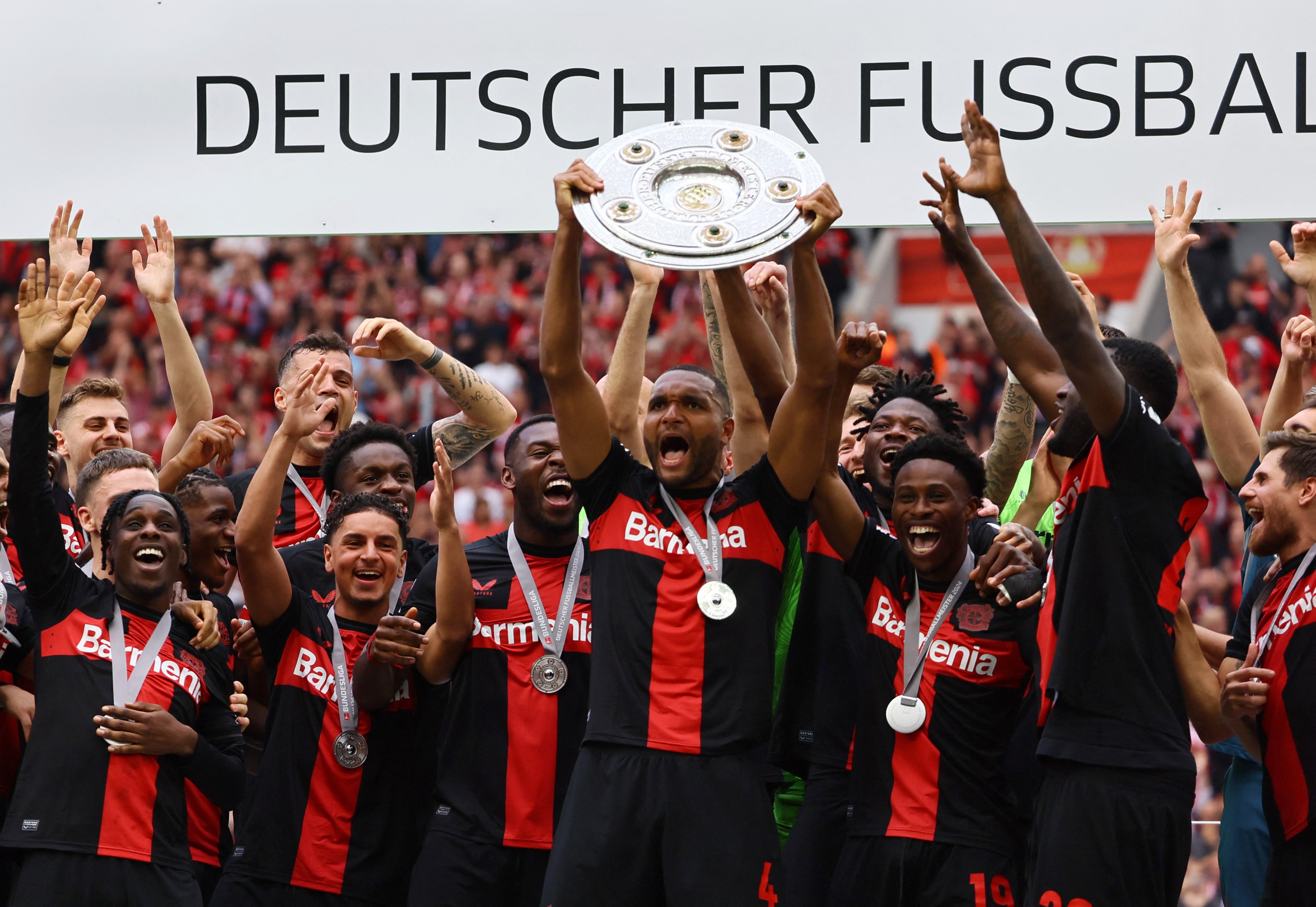 Bayer Leverkusen's Jonathan Tah celebrates with the trophy and teammates after winning the Bundesliga and going unbeaten