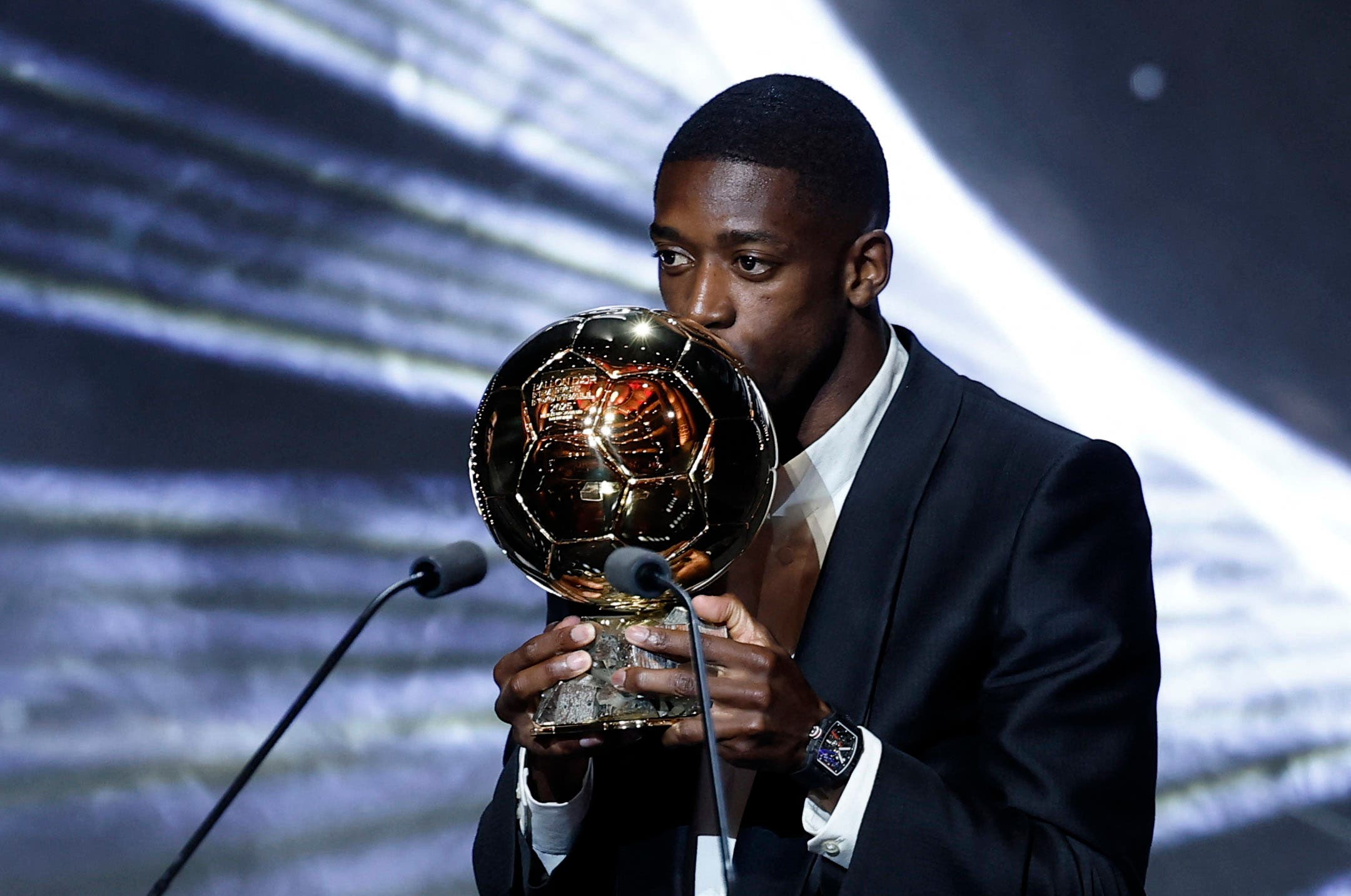 Ousmane Dembélé kisses the Ballon D'Or trophy.