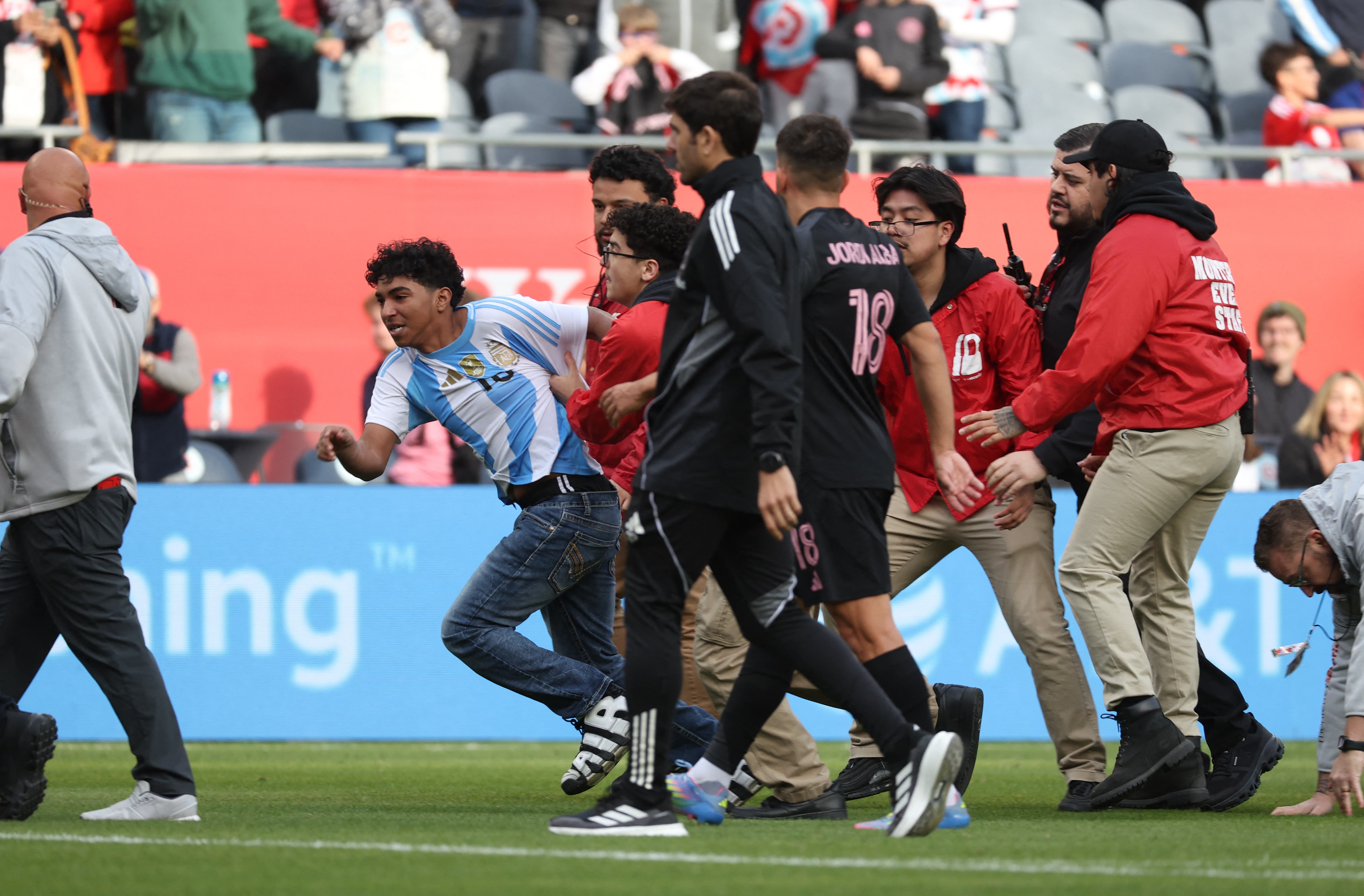 Apr 13, 2025; Chicago, Illinois, USA; A pitch invader breaks loose from security guards while attempting to get a selfie with Inter Miami CF forward Lionel Messi (10, not pictured) following a match between Chicago Fire FC and Inter Miami CF at Soldier Field. Mandatory Credit: Talia Sprague-Imagn Images