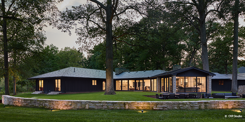 after renovations; back of house well-lit expansive windows and doors in the evening