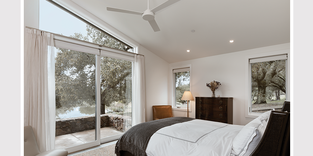 Guest bedroom that leads out to deck, featuring pati-door and custom geometric window